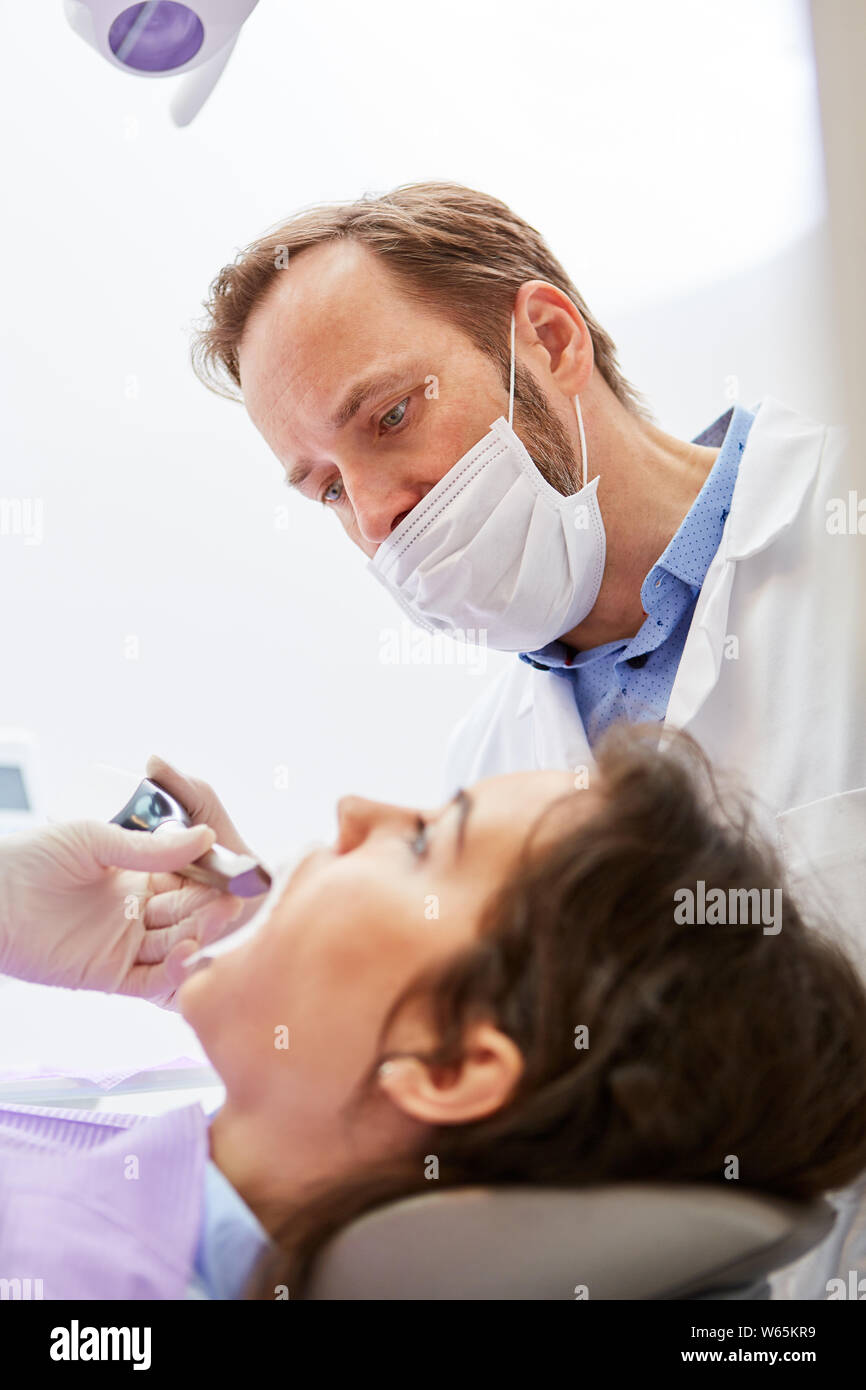 Dentista con maschera e paziente al professional sbiancamento dei denti nella clinica dentale Foto Stock