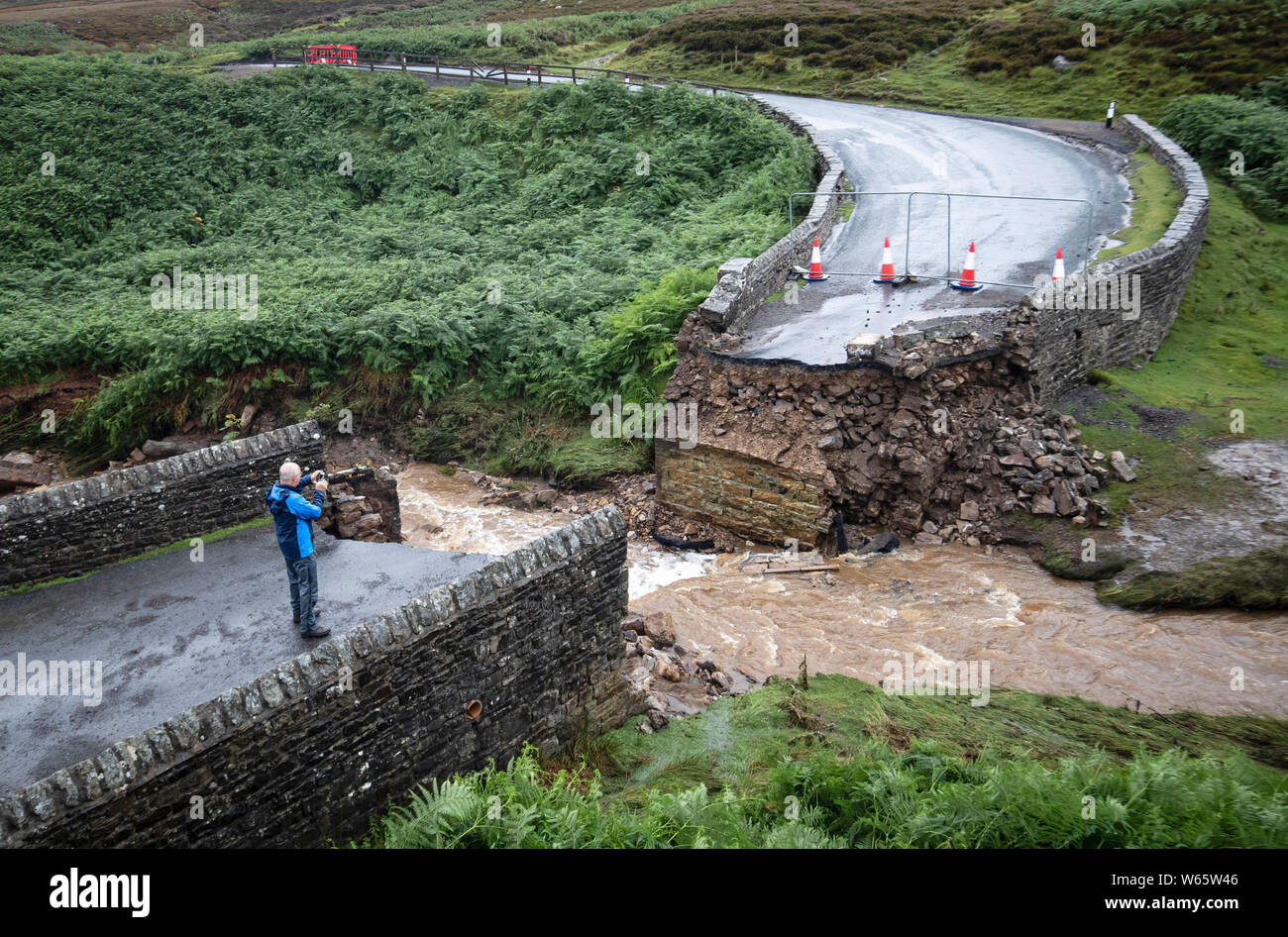 Un uomo prende una fotografia di un ponte crollato vicino Grinton, North Yorkshire, dopo le parti della regione avevano fino a 82.2mm di pioggia in 24 ore il martedì. Foto Stock