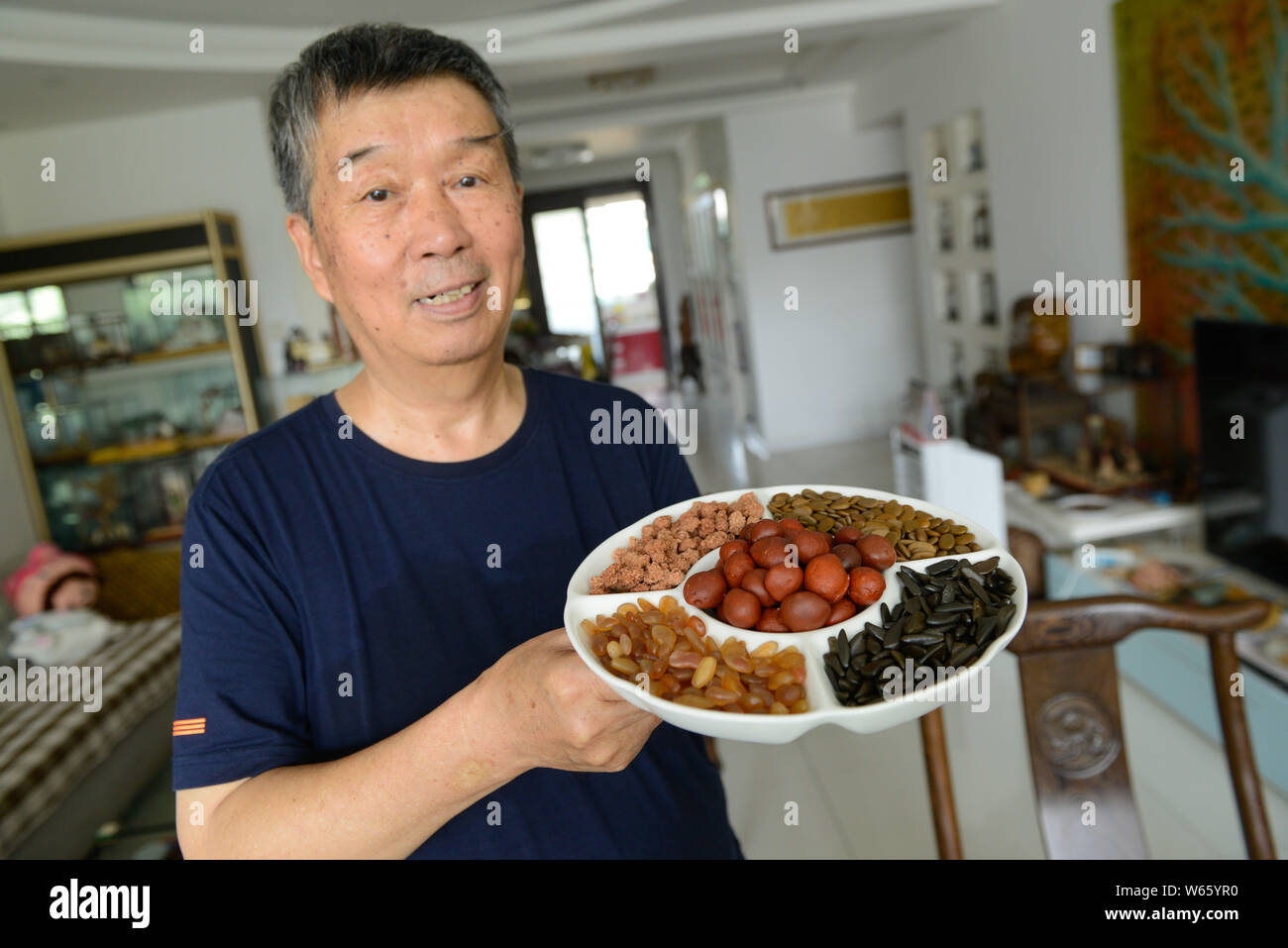 Il cinese anziano uomo Yan Baosheng mostra le pietre colorate che assomigliano a semi di melone e il dado frutti di Taiyuan, città del nord della Cina nella provincia dello Shanxi, 28 agosto Foto Stock