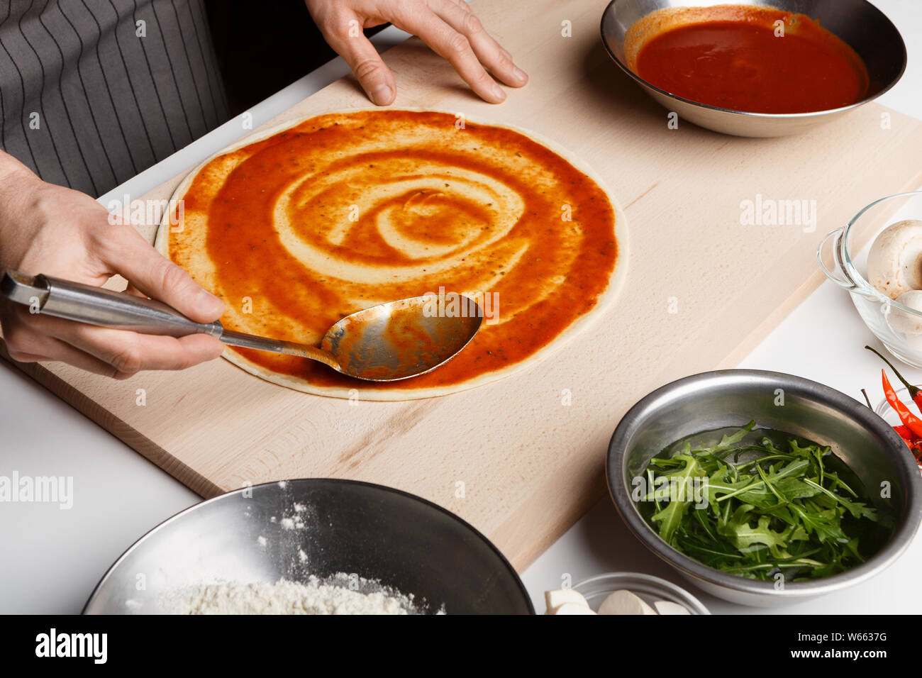 Lo Chef diffusione di pasta di pomodoro sulla base per pizza Foto Stock