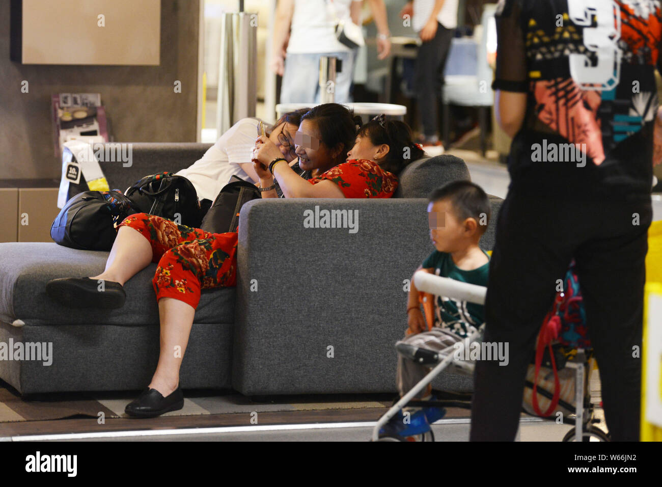 Locali residenti cinese di sonno o di riposo sui divani in un negozio di arredamento di IKEA per sfuggire al caldo nella città di Nanjing East cinese della provincia di Jiangsu, 11 Lug Foto Stock