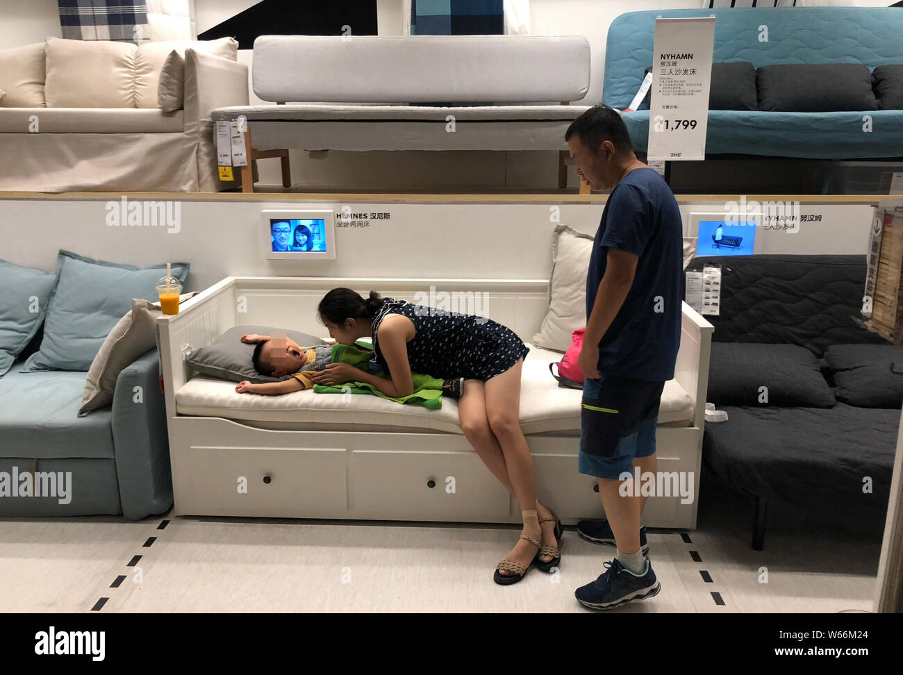 Un giovane cinese guarda al loro figlio di dormire su un divano letto con  un aria