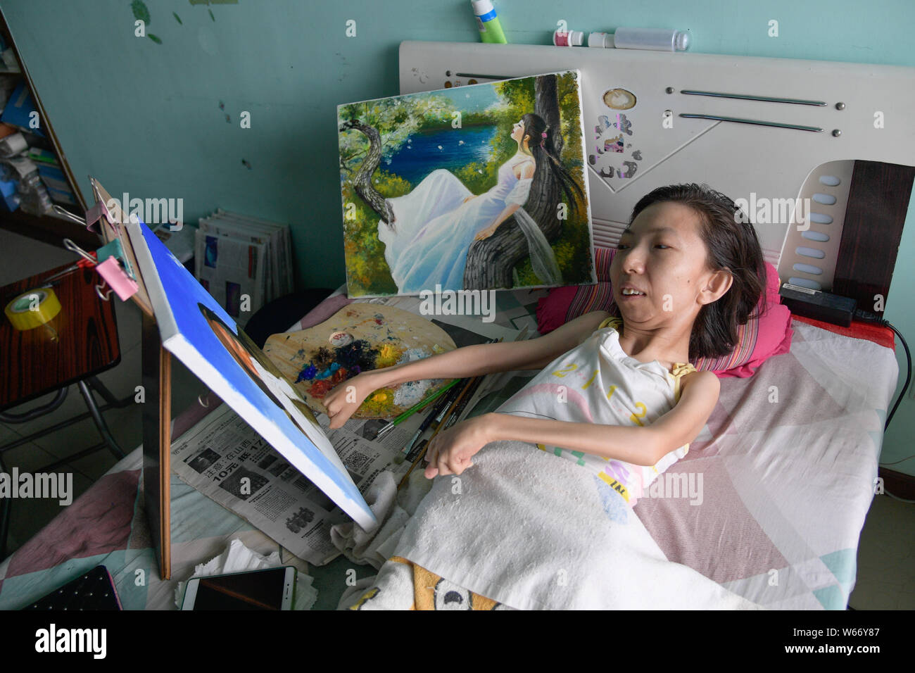 Il 40-anno-vecchio donna cinese Zhang Junli, che ha paralizzato da lei era di otto, crea un dipinto ad olio su letto di casa nella città di Taiyuan, nord C Foto Stock
