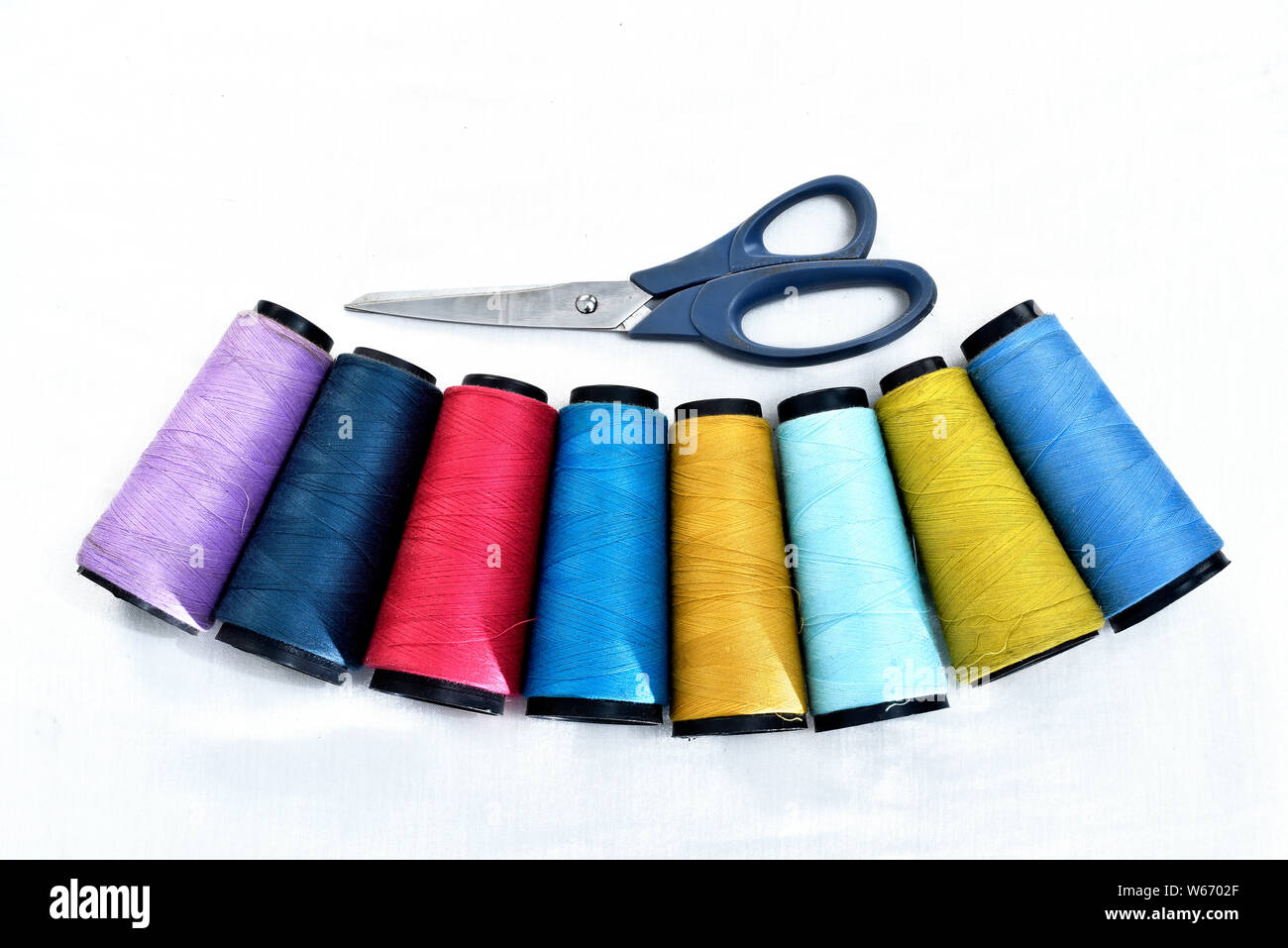 Colorata per cucire bobine su sfondo bianco con le forbici. Foto Stock