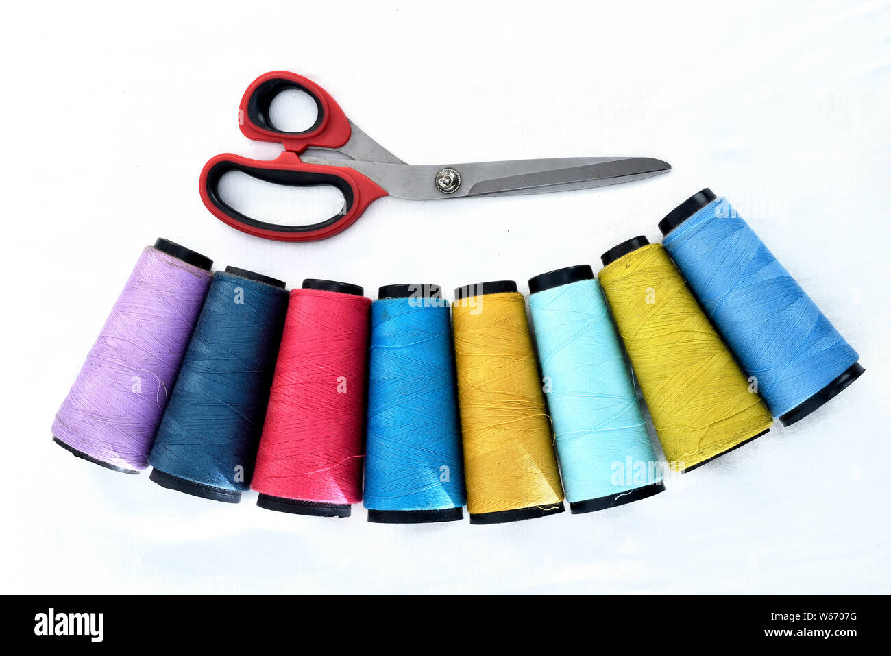 Colorata per cucire bobine su sfondo bianco con le forbici. Foto Stock