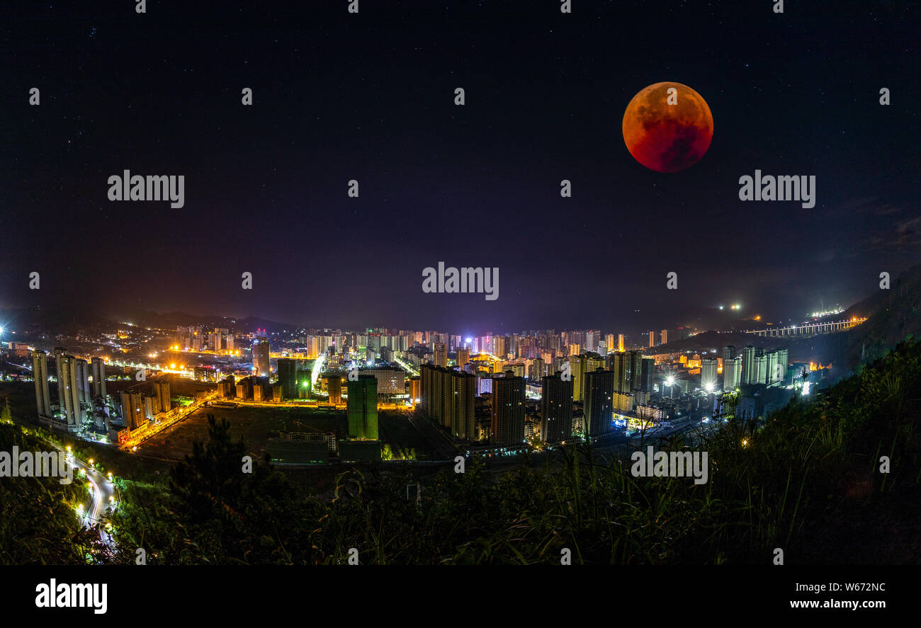 Vista la più lunga "sangue luna' eclissi di questo secolo che passa nel cono d'ombra della Terra, nel cielo sopra i grattacieli durante una totale e lunare Foto Stock