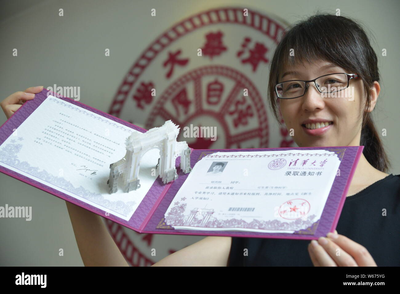 Un insegnante mostra il 2018 Università Tsinghua lettera di accettazione con un 3D carta scultura di il simbolico secondo cancello ¨C 'Vecchio Gate' del collegio Foto Stock