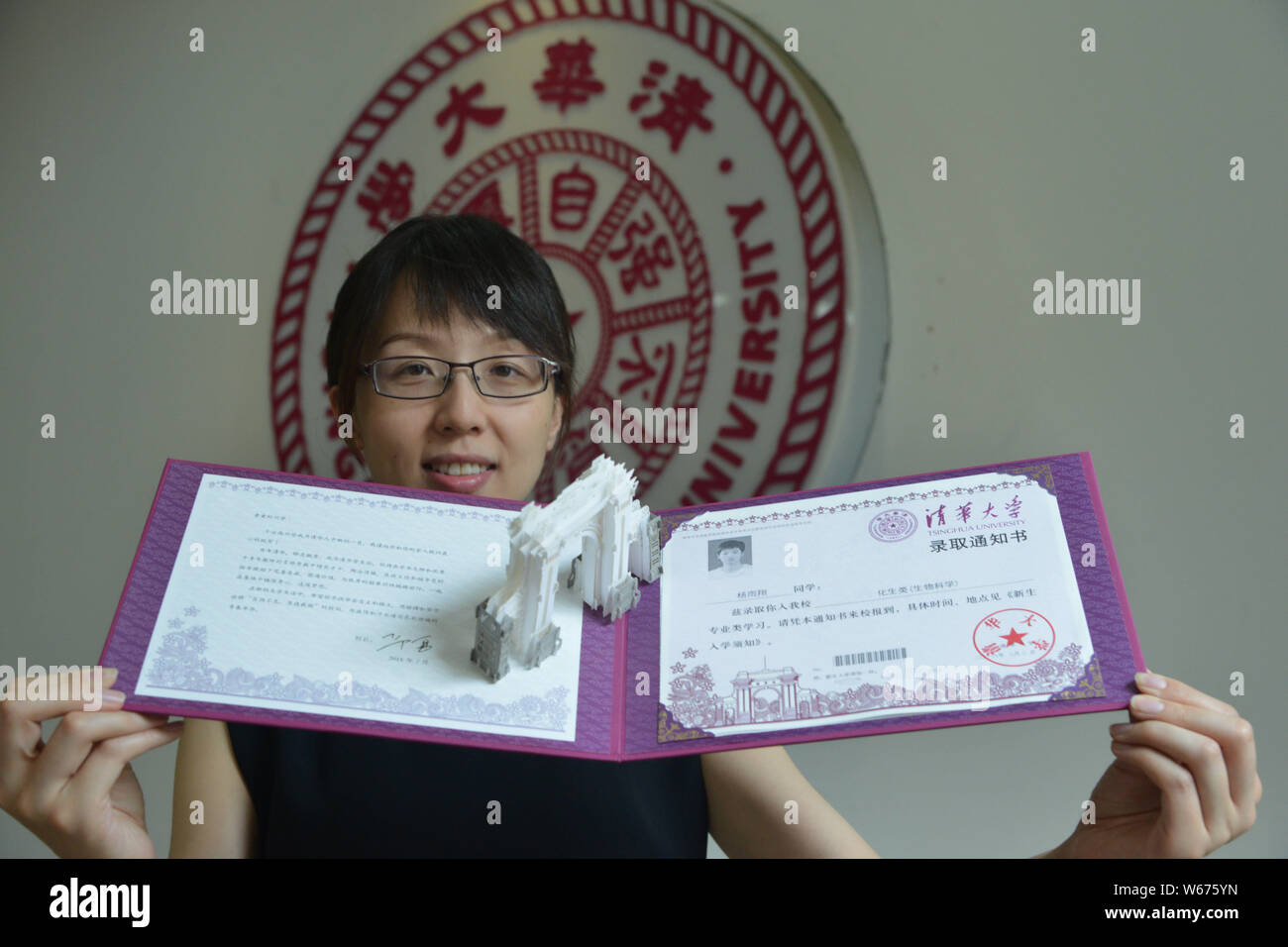 Un insegnante mostra il 2018 Università Tsinghua lettera di accettazione con un 3D carta scultura di il simbolico secondo cancello ¨C 'Vecchio Gate' del collegio Foto Stock