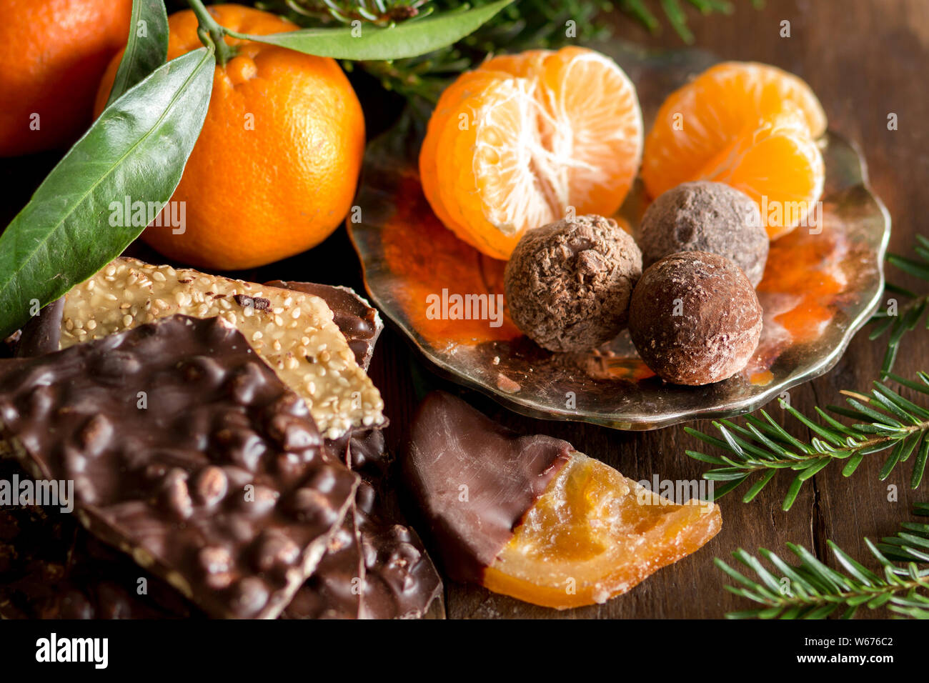 Cioccolato, tartufi e tangerins con l'abete su un tavolo di legno Foto Stock