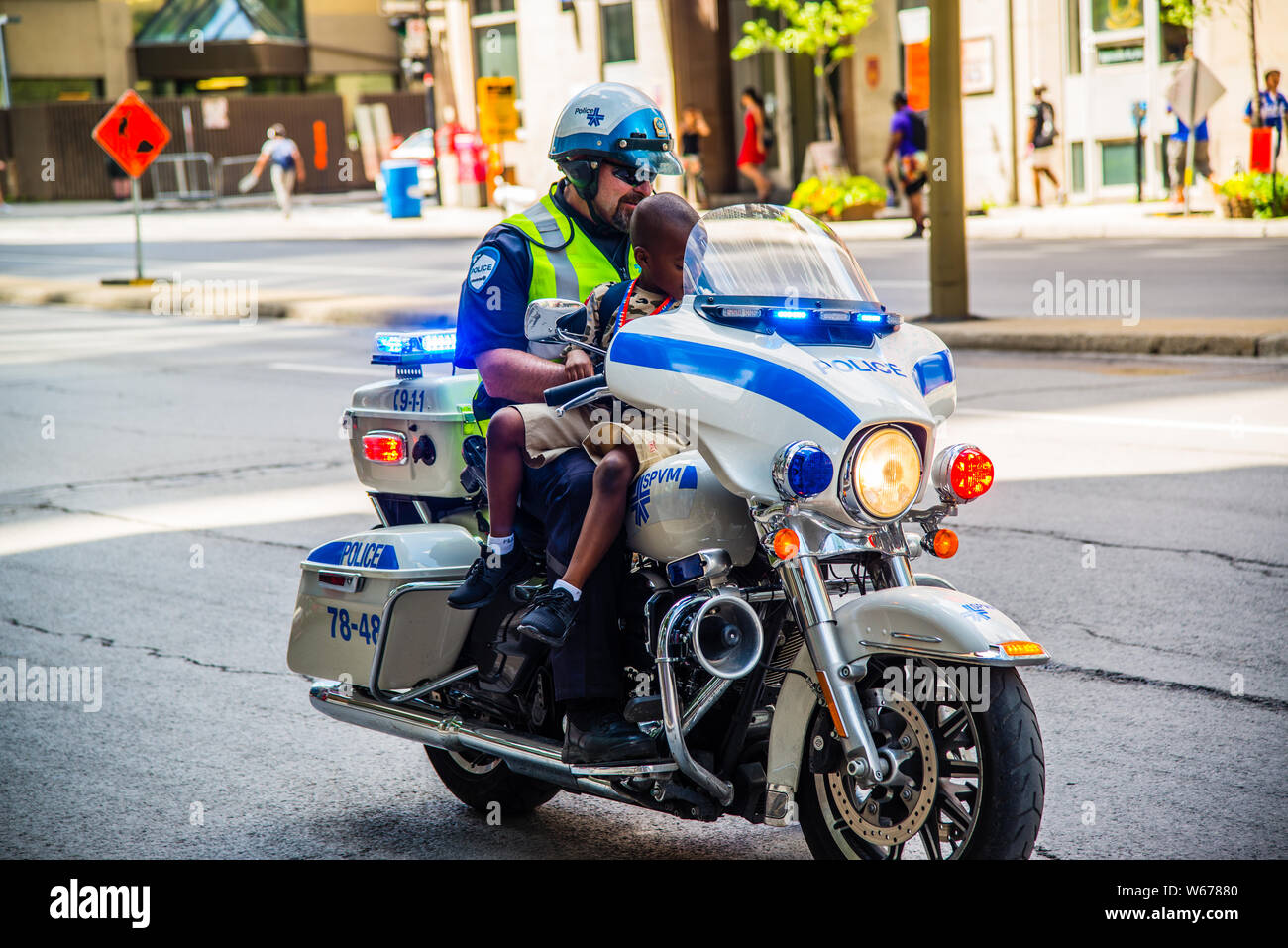 Funzionario di polizia nel centro cittadino di Montreal sulla moto con un capretto Foto Stock