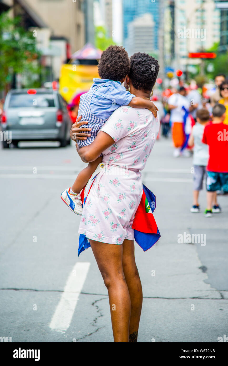 Una madre mentre tiene il suo bambino in piedi in strada nel centro di Montreal Foto Stock
