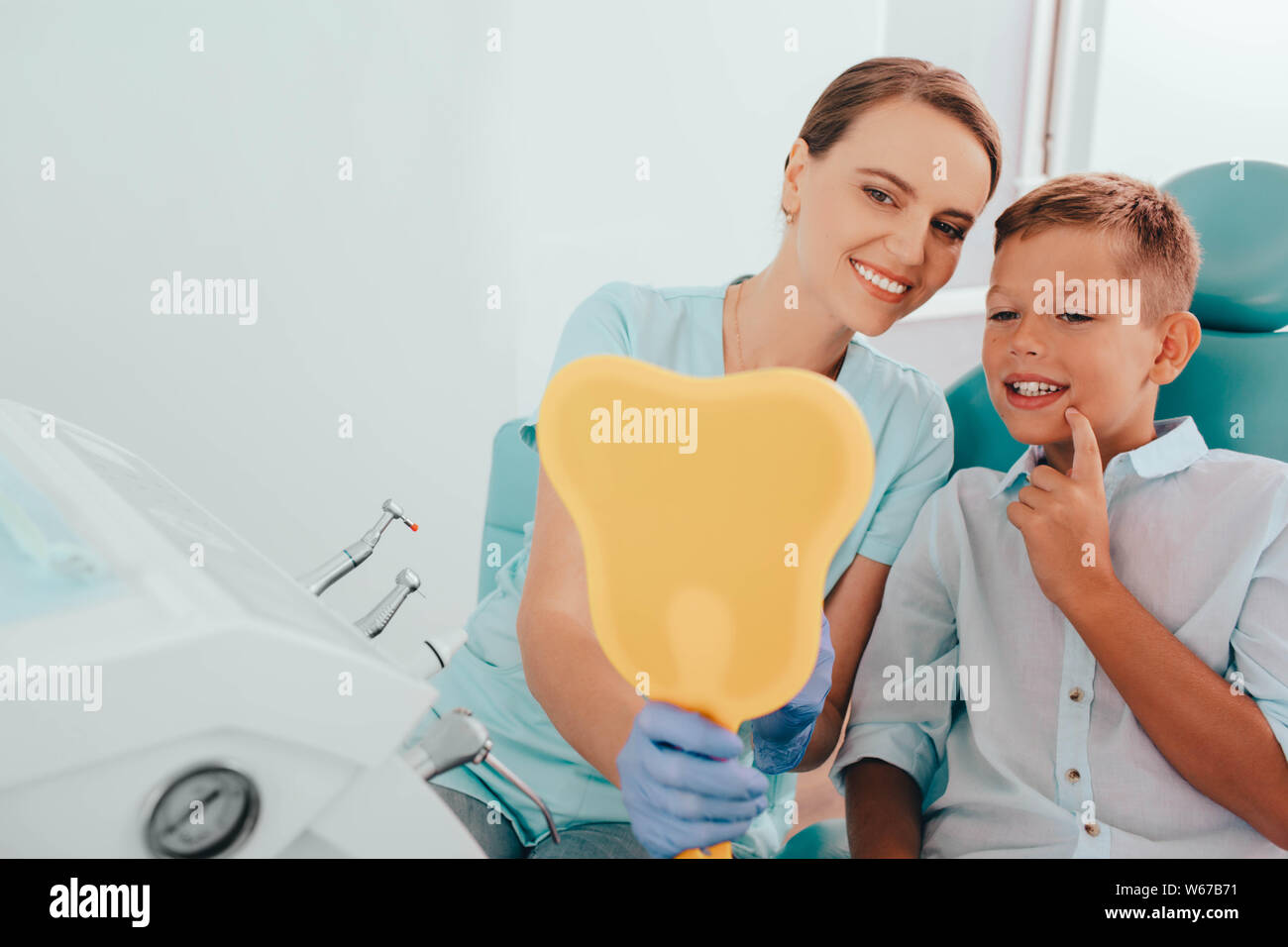Piccolo paziente ed il suo medico dentista sorridendo dopo aver superato con successo il trattamento dentale. Essi cercando in specchio sulla perfetta dei denti sani Foto Stock