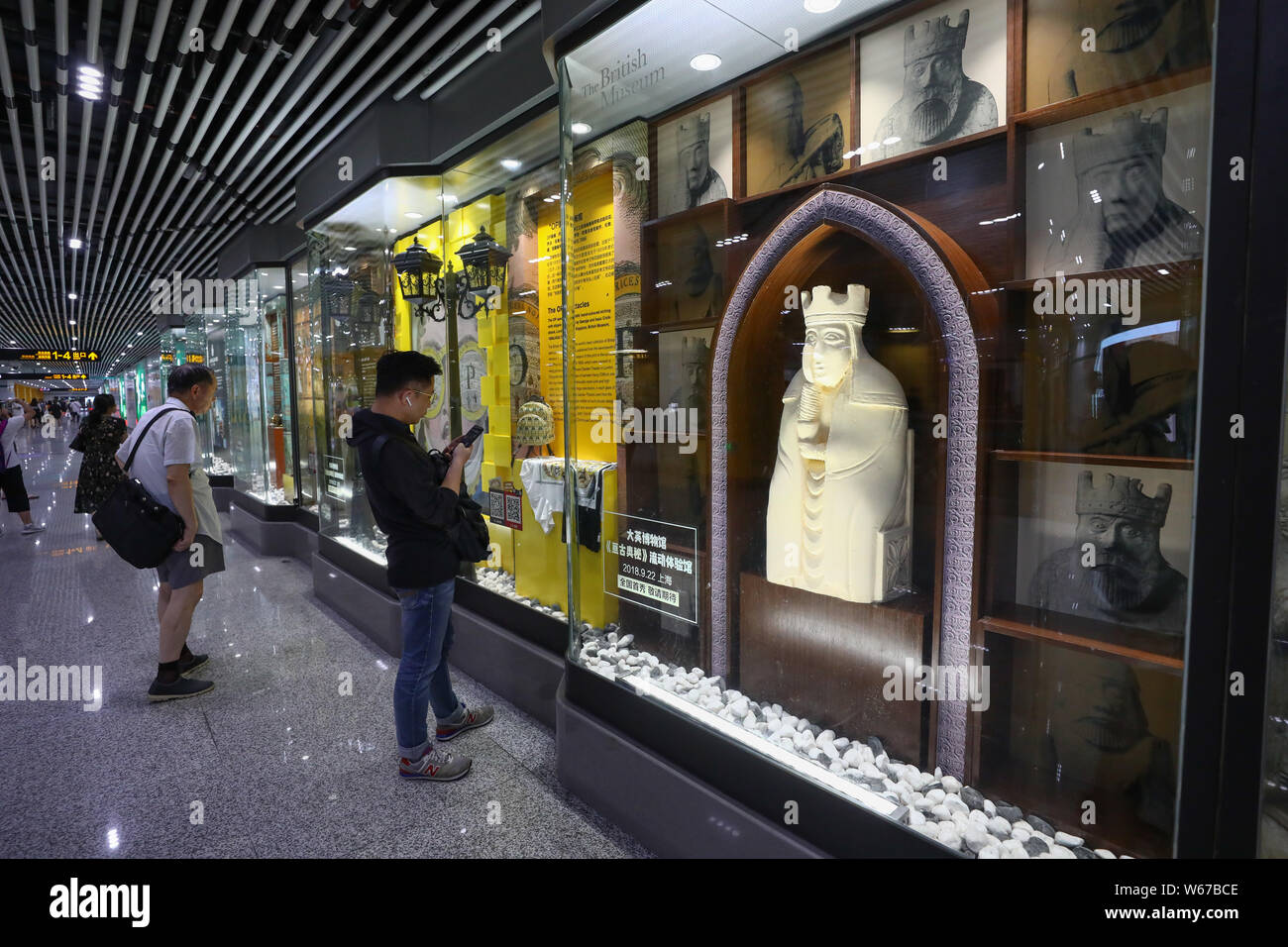 Passeggeri Guardare le riproduzioni di opere d'arte dal British Museum di collezione in mostra presso il South Shaanxi Road dalla stazione della metropolitana di Shanghai, mento Foto Stock