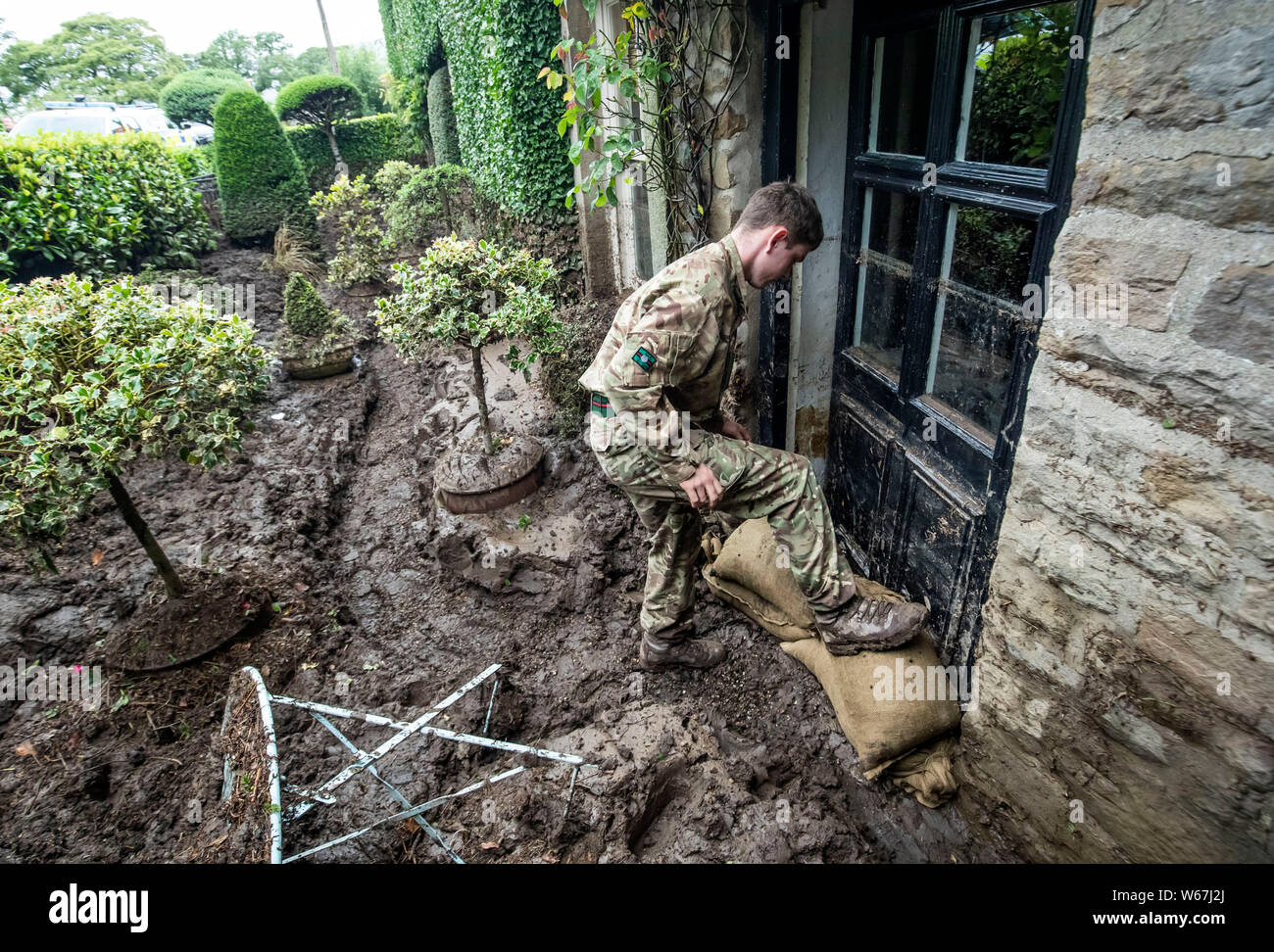 Un soldato da 2 Yorks Stack i sacchi di sabbia in Grinton, North Yorkshire dopo che parti della regione avevano fino a 82.2mm di pioggia in 24 ore il martedì. Foto Stock