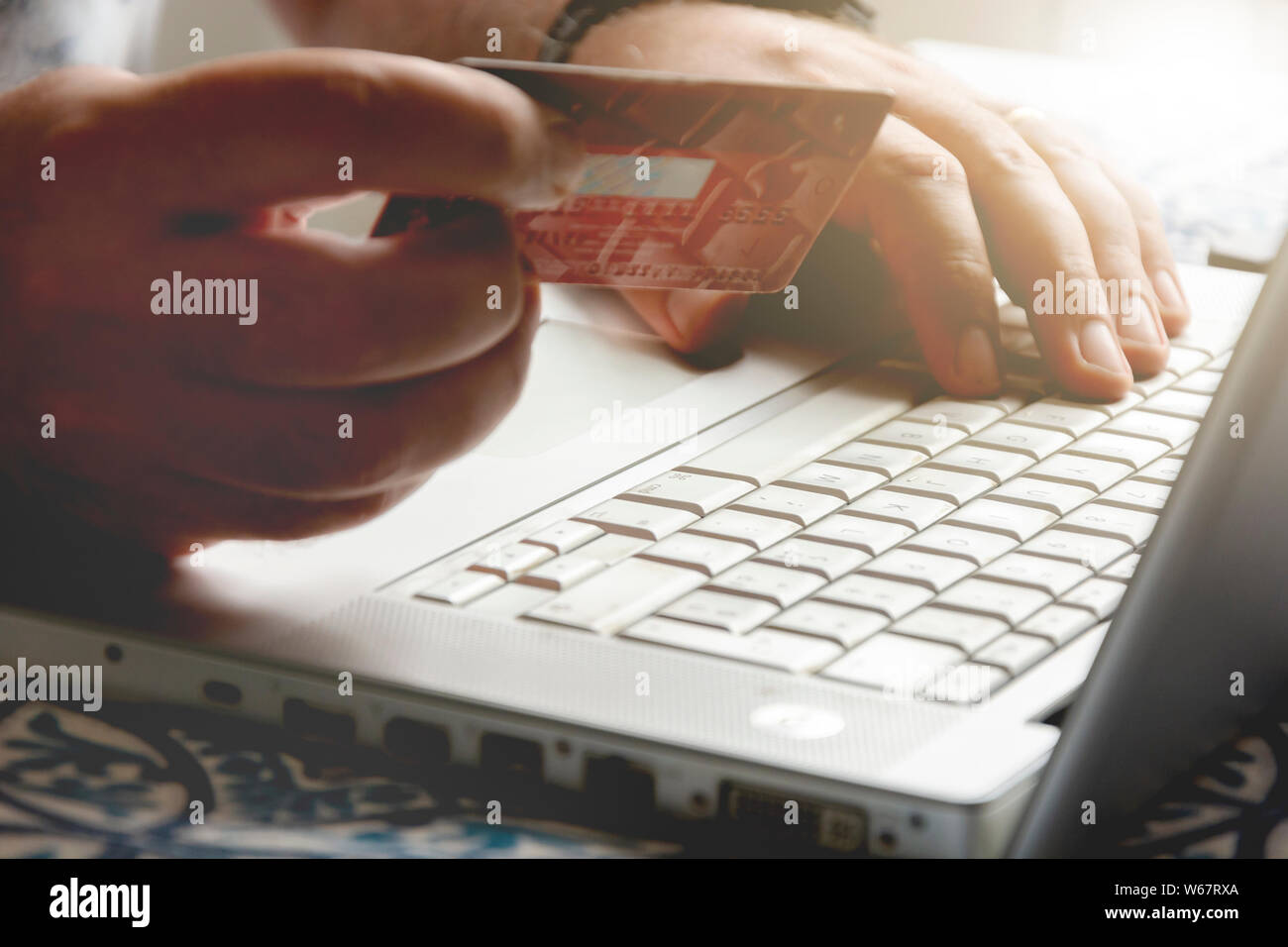 Mano di sesso maschile in possesso di una carta di credito durante il pagamento via internet transazione. Concetto di e-commerce e shopping on line. Foto Stock