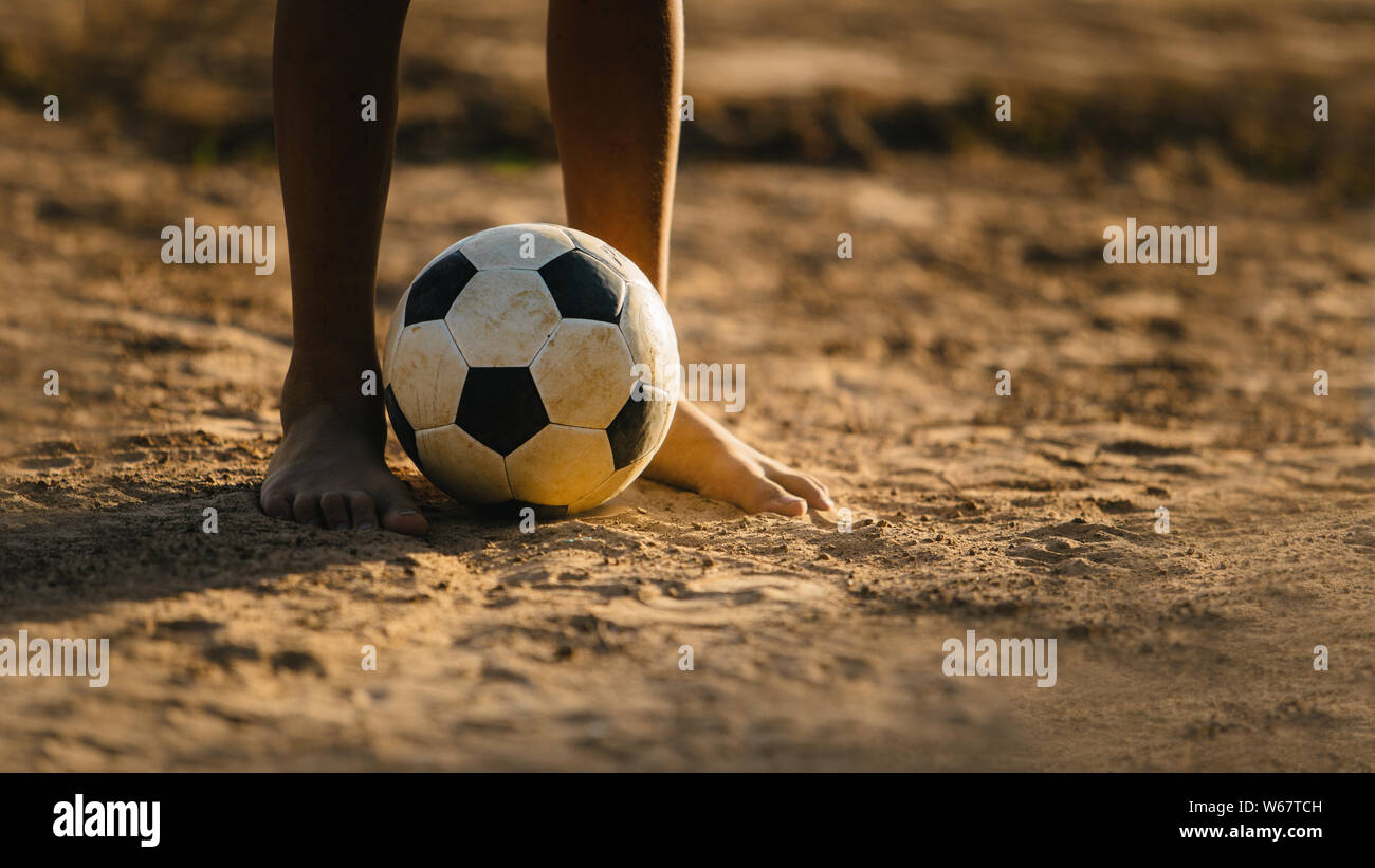 Azione sport all aperto di ragazzi che giocano a calcio per esercitare nella Comunità area rurale sotto il crepuscolo del tramonto. Poveri e la povertà dei bambini. Foto Stock