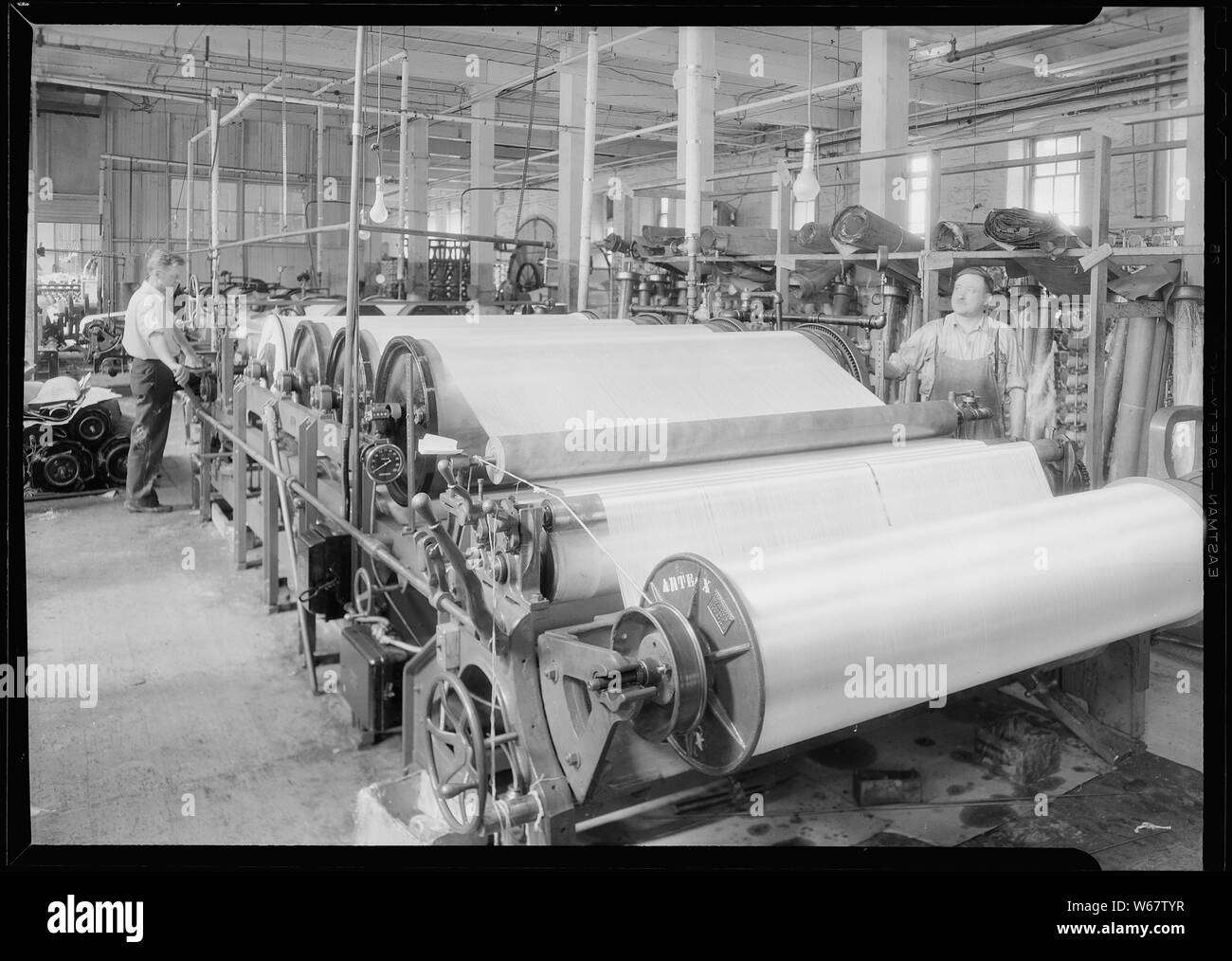 Paterson, New Jersey - Prodotti tessili. Avvolgimento di Jackson e società di orditura Nederlands : Cylindersterkmachine; Portata e contenuto: Paterson, New Jersey - Prodotti tessili. Avvolgimento di Jackson e società di orditura. Immagine di un Charles B. Johnson dimensionamento della macchina. Questa è l'ultima ad alta velocità macchina di dimensionamento ed è noto come un sette può digitare. Il tessuto passa attraverso la macchina alla velocità di 80 metri al minuto e può fare un cantiere 1.200 ordito in circa 45 minuti. Questa stima del tempo include la legatura e la rimozione dei fili di ordito. Queste macchine di dimensionamento venite con un numero diverso di lattine. I cinque può tipo può fare circa Foto Stock