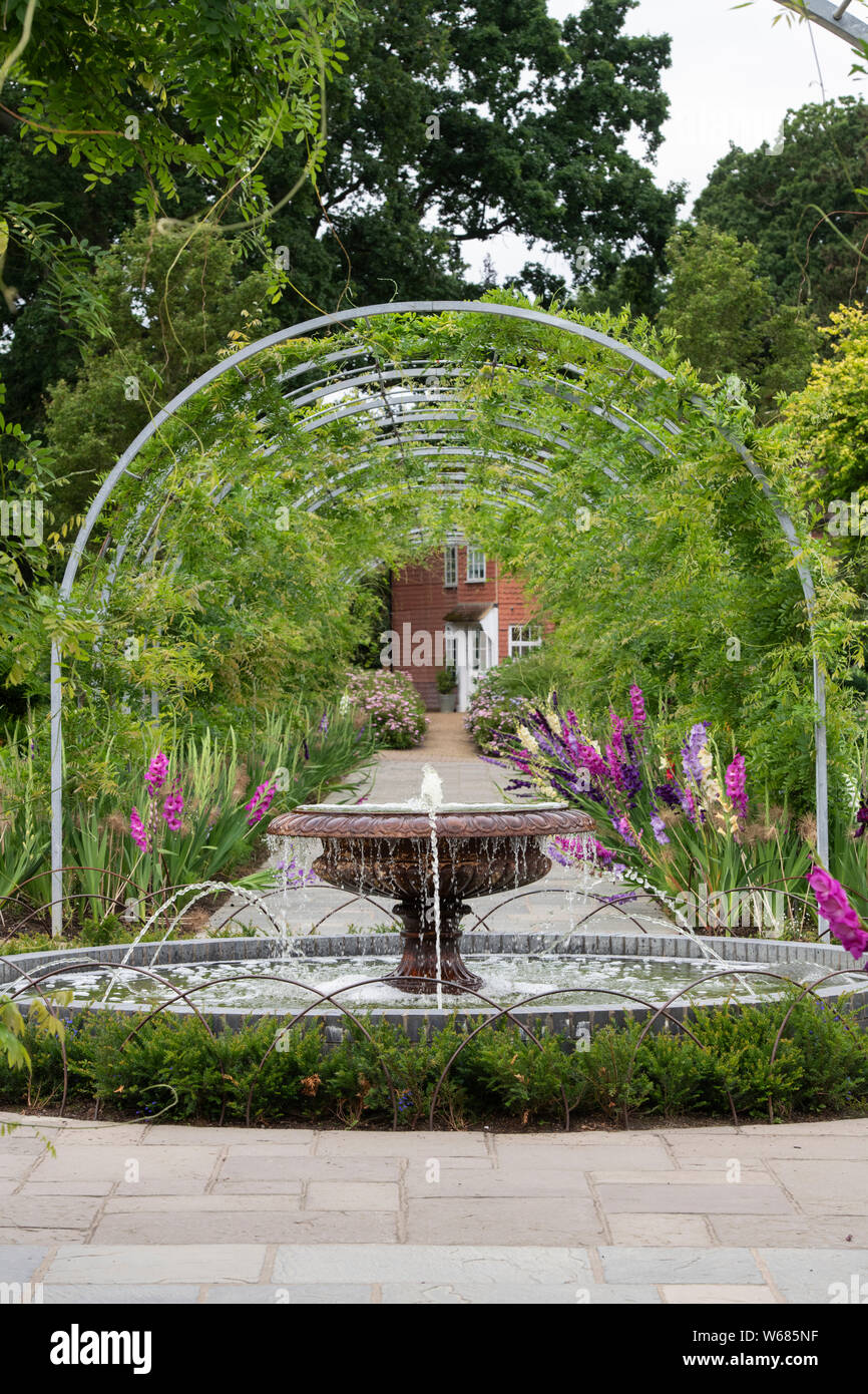 Funzione acqua e wisteria archway ad RHS Wisley Gardens, Surrey, Regno Unito Foto Stock