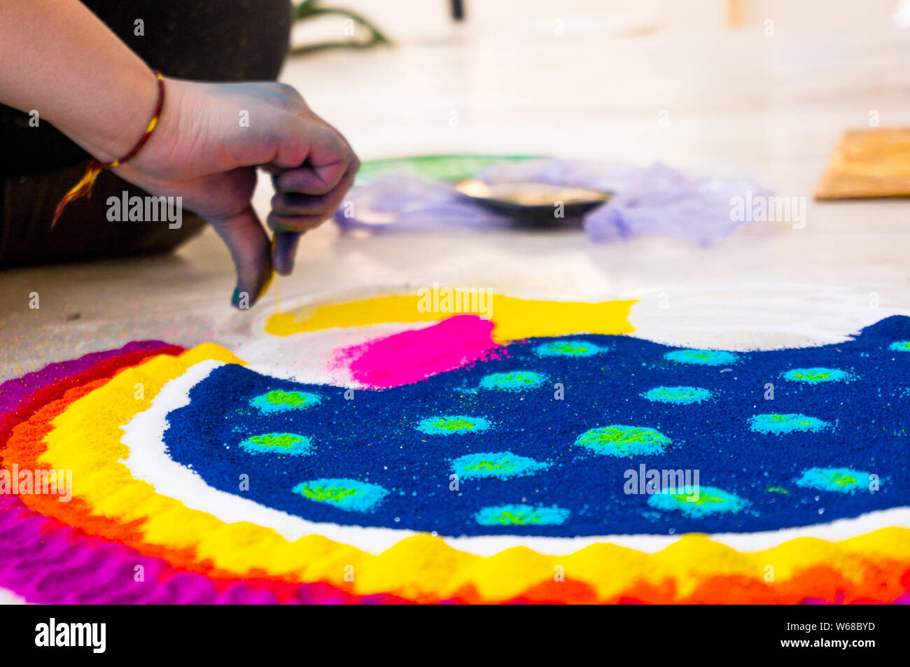 La mano del giovane ragazza indiana rendendo rangoli dalla polvere colorata il Diwali eve. Questi bellissimi disegni sono realizzati in ogni casa indù per decorare e celeb Foto Stock