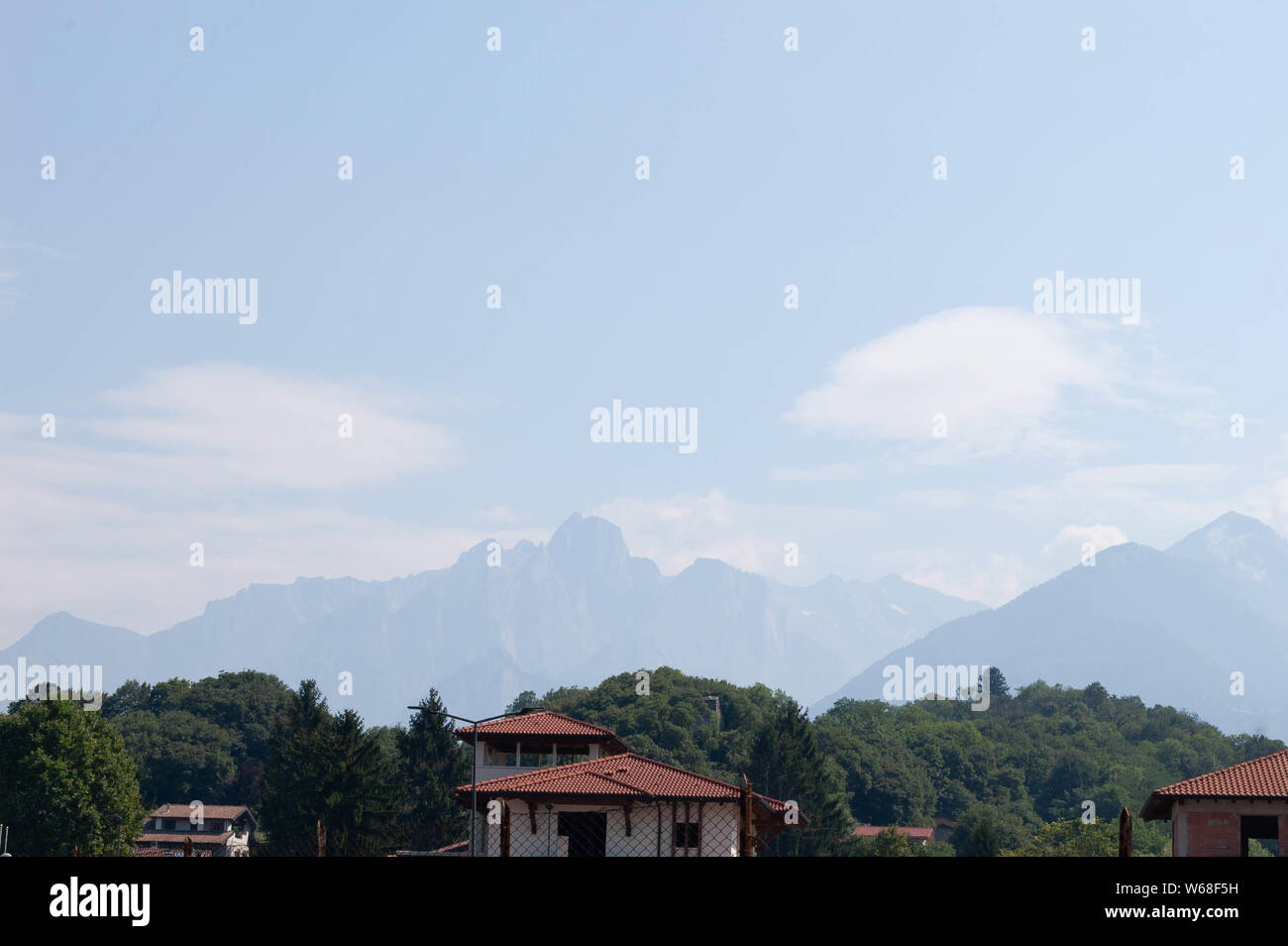 Alp montagne dietro le case della città di Colico in Como lake district, Italia. Sunny luminosa giornata d'estate.. Foto Stock