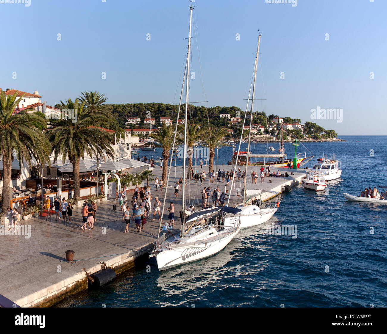 Persone, ristoranti e una vasta gamma di barche di animare Hvar La Riva promenade, un popolare croato cruise port. Foto Stock