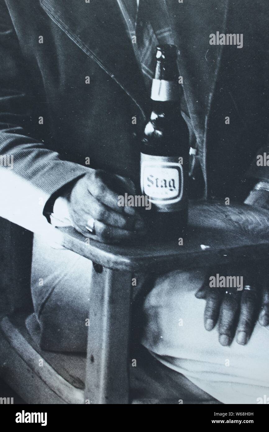 Bene in bianco e nero fotografia d'arte dagli anni settanta di un vecchio americano africano uomo beve una bottiglia di birra Stag. Foto Stock
