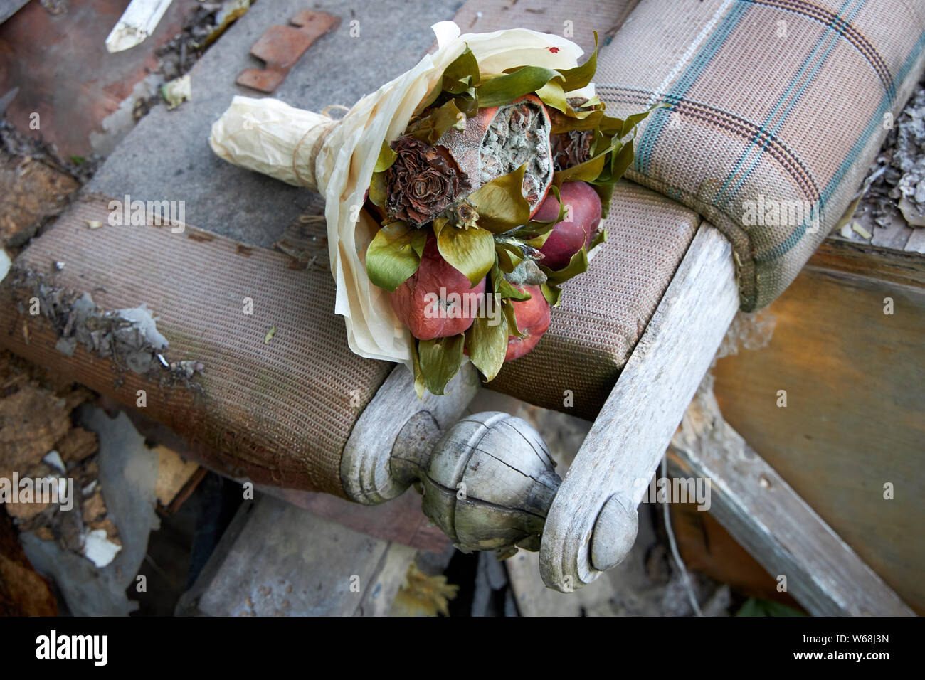 Mazzetto di marcio frutta e fiori appassito stendere sui resti di mobili rotti Foto Stock