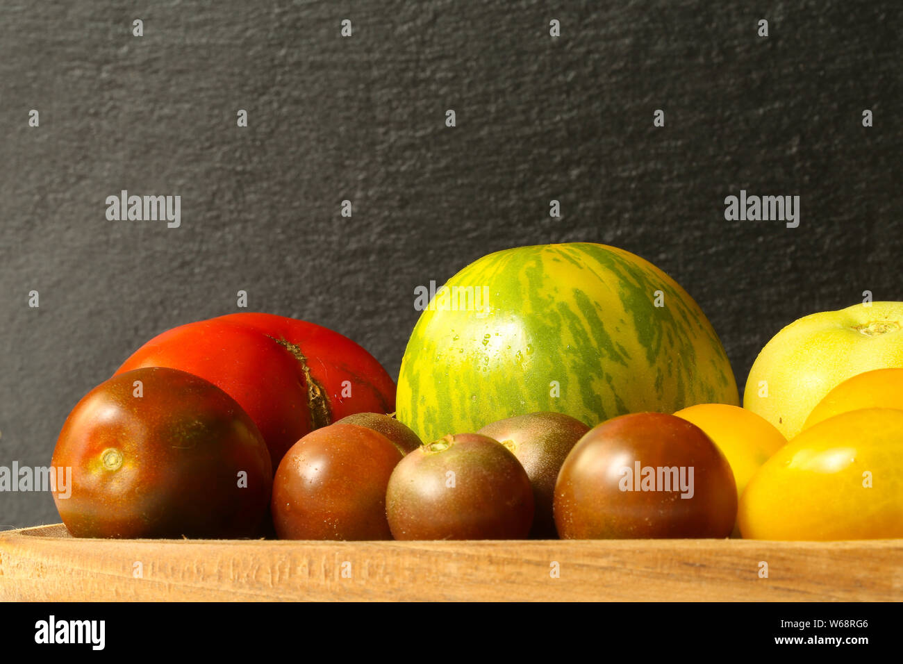 Rote Tomaten auf Holzbrett auf schwarzem Schiefer Hintergrund Foto Stock