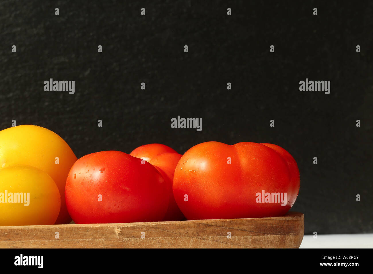 Rote Tomaten auf Holzbrett auf schwarzem Schiefer Hintergrund Foto Stock