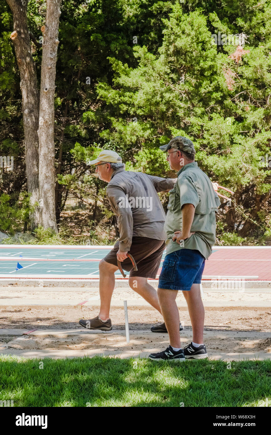 Due uomini anziani che giocano a carping horseshoes in una comunità di anziani di Sun City, Texas. Foto Stock