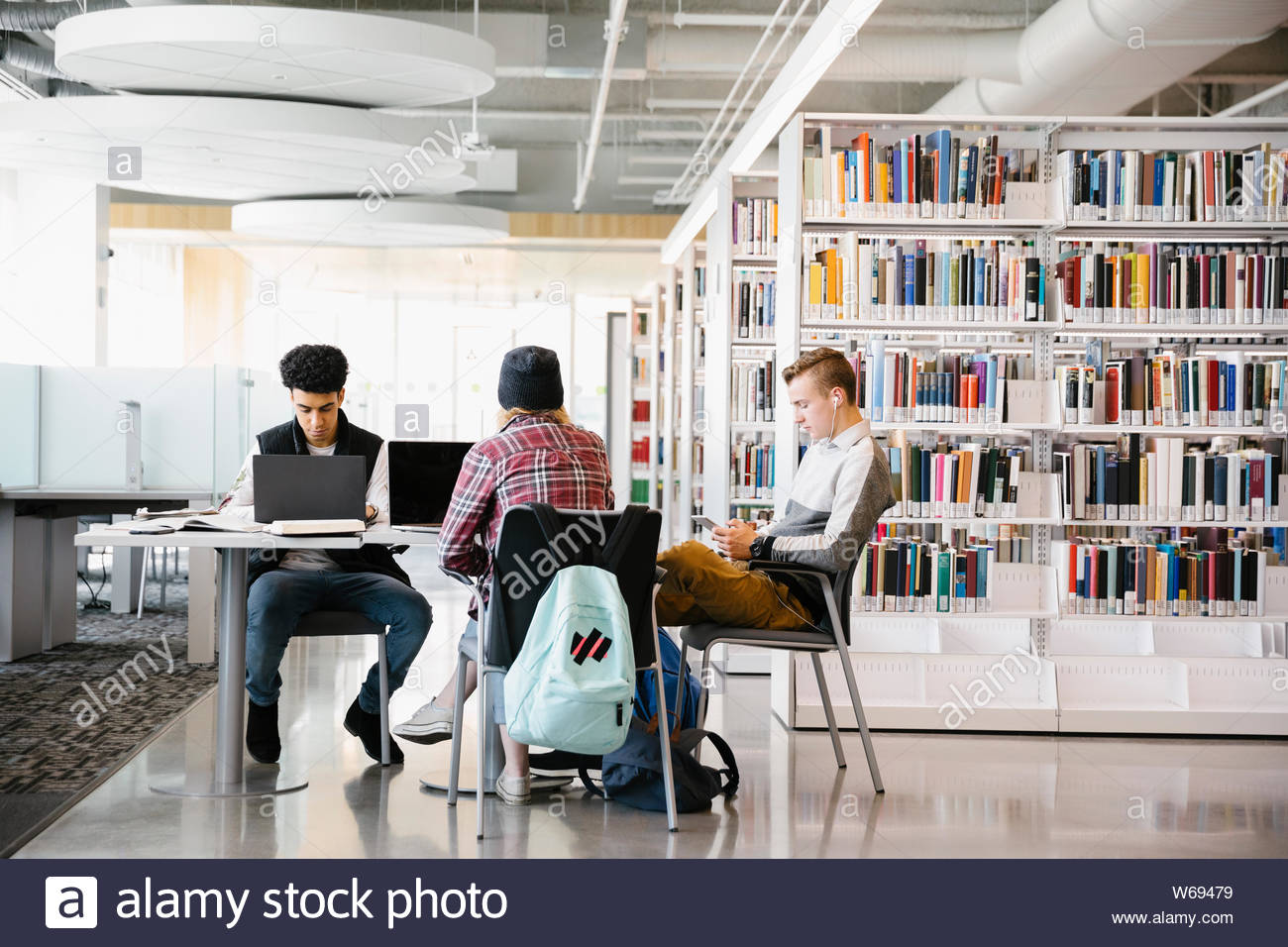 Tre studenti che studiano in biblioteca universitaria Foto Stock