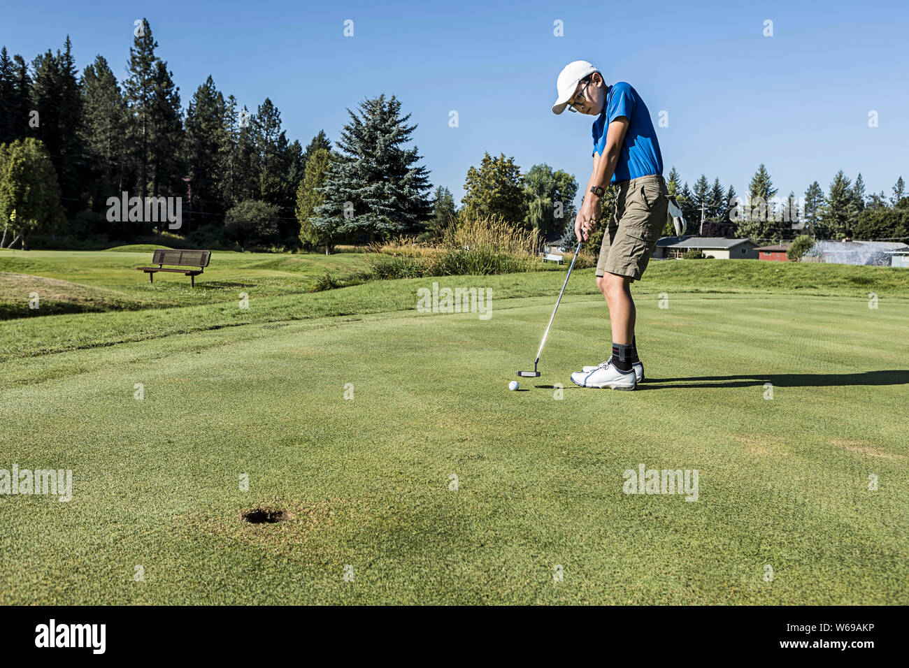 Un vecchio ragazzo fa un putt su una luminosa e soleggiata giornata in Coeur d'Alene, Idaho. Foto Stock