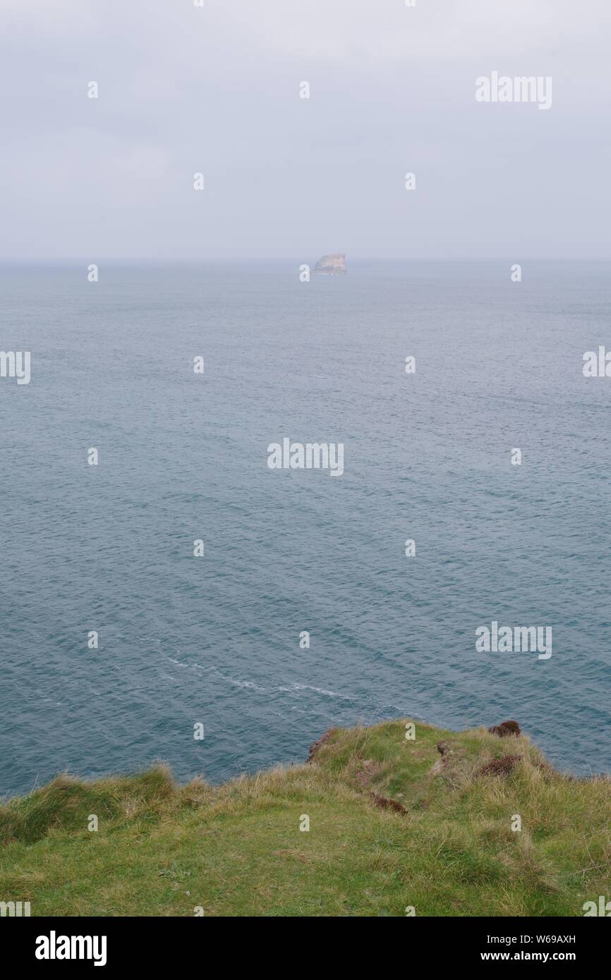 Bawden rocce isola sul fieno orizzonte al di là di un calmo mare verde smeraldo, dalla rupe di Sant Agnese di testa. North Cornwall, Regno Unito. Foto Stock