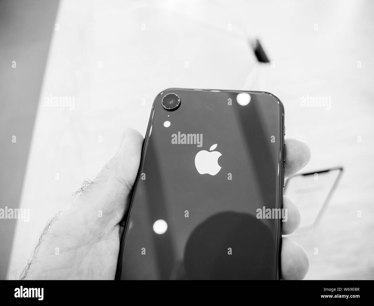 Parigi, Francia - Ott 26, 2018: Man mano che tiene iPhone più recente XR smartphone durante il giorno del lancio è fabbricato da Apple Computer ammirando il logo sulla parte posteriore - bianco e nero Foto Stock