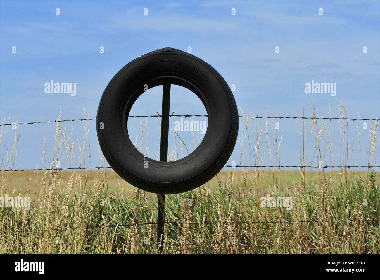 Pneumatico nero su una recinzione barbwire con il blu del cielo. Foto Stock