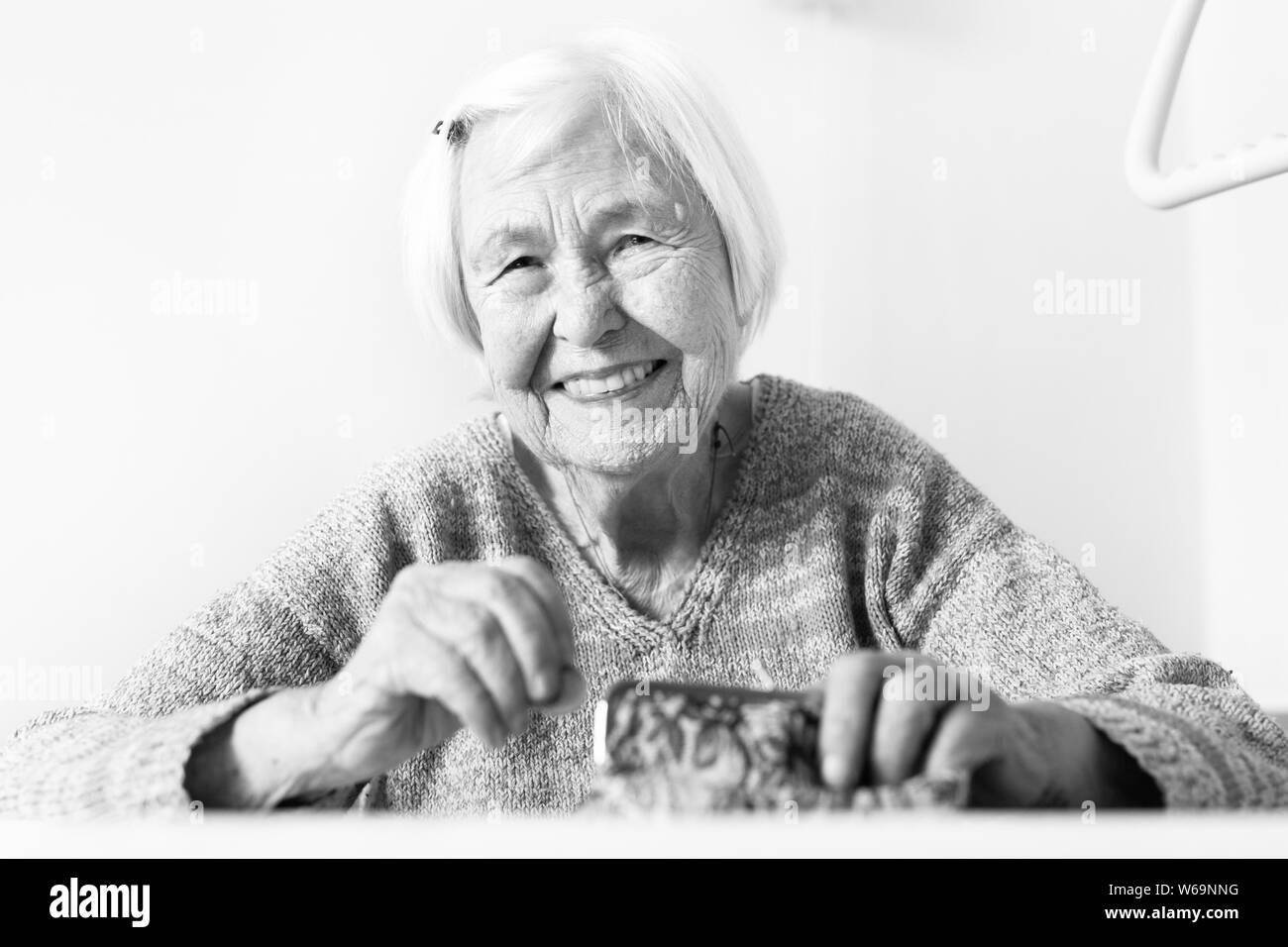 Allegro anziani 96 anni donna seduta al tavolo a casa felice con la sua pensione risparmi nel suo portafoglio dopo il pagamento di fatture. In bianco e nero. Foto Stock