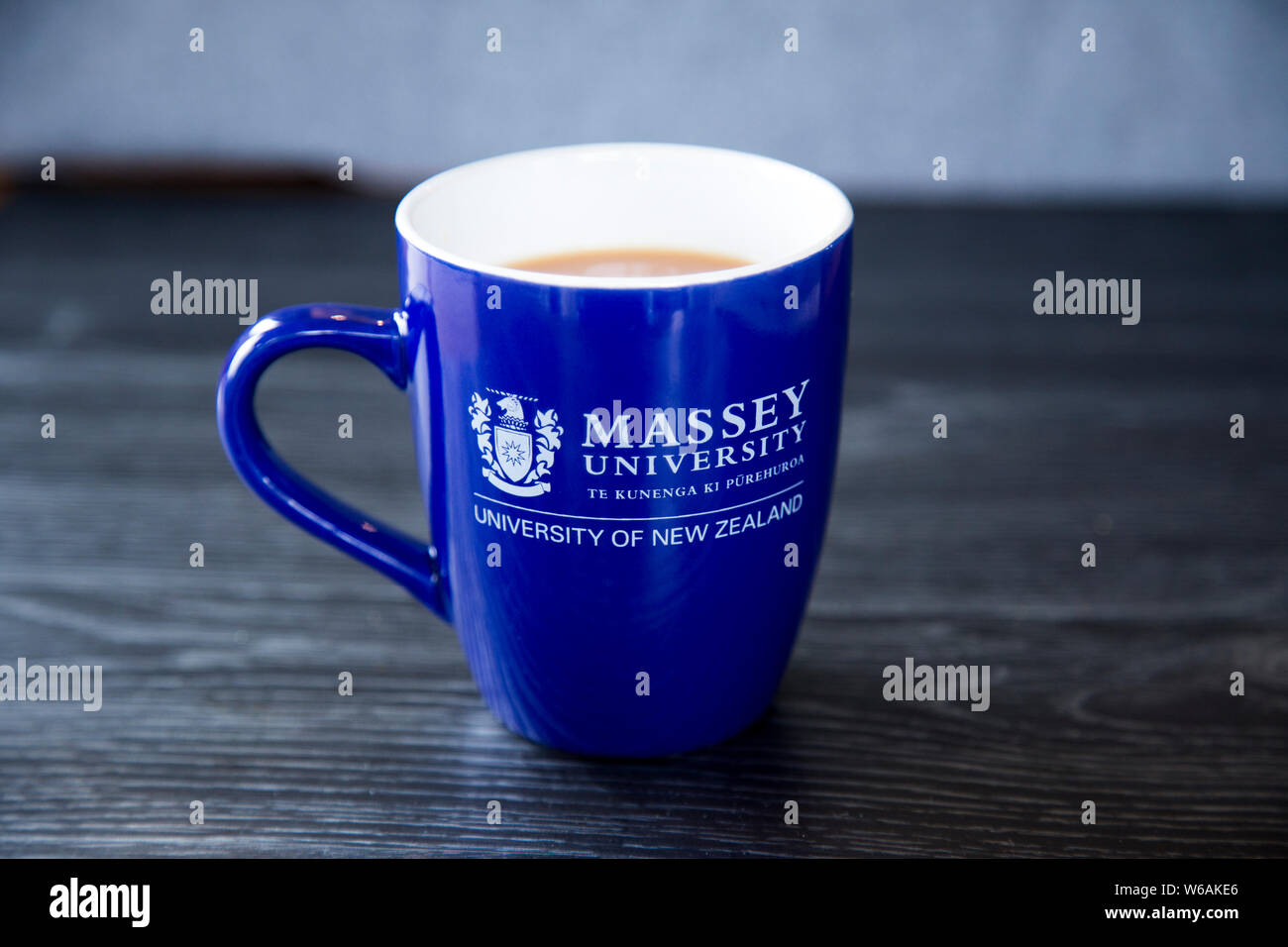 Calda tazza di tè realizzato in una tazza di colore blu con il marchio di Massey University. Raffigura un concetto rilassante con un fresco schema di colore di blu e grigio. Foto Stock