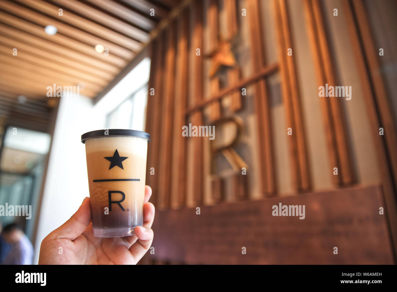 Una cliente mostra una tazza di caffè presso il nuovissimo flagship store di riserva di Starbucks a Pechino in Cina, 29 giugno 2018. Il gigante del caffè Starbucks Foto Stock