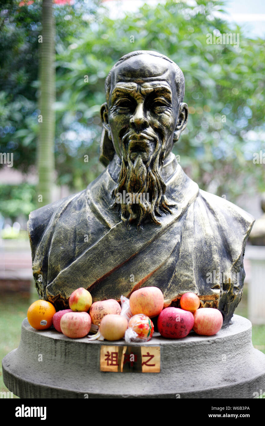 Una statua di bronzo di antichi cinesi matematico Zu Chongzhi è abbracciato da mele e altri frutti con benedizioni scritto da studenti sulle superfici Foto Stock