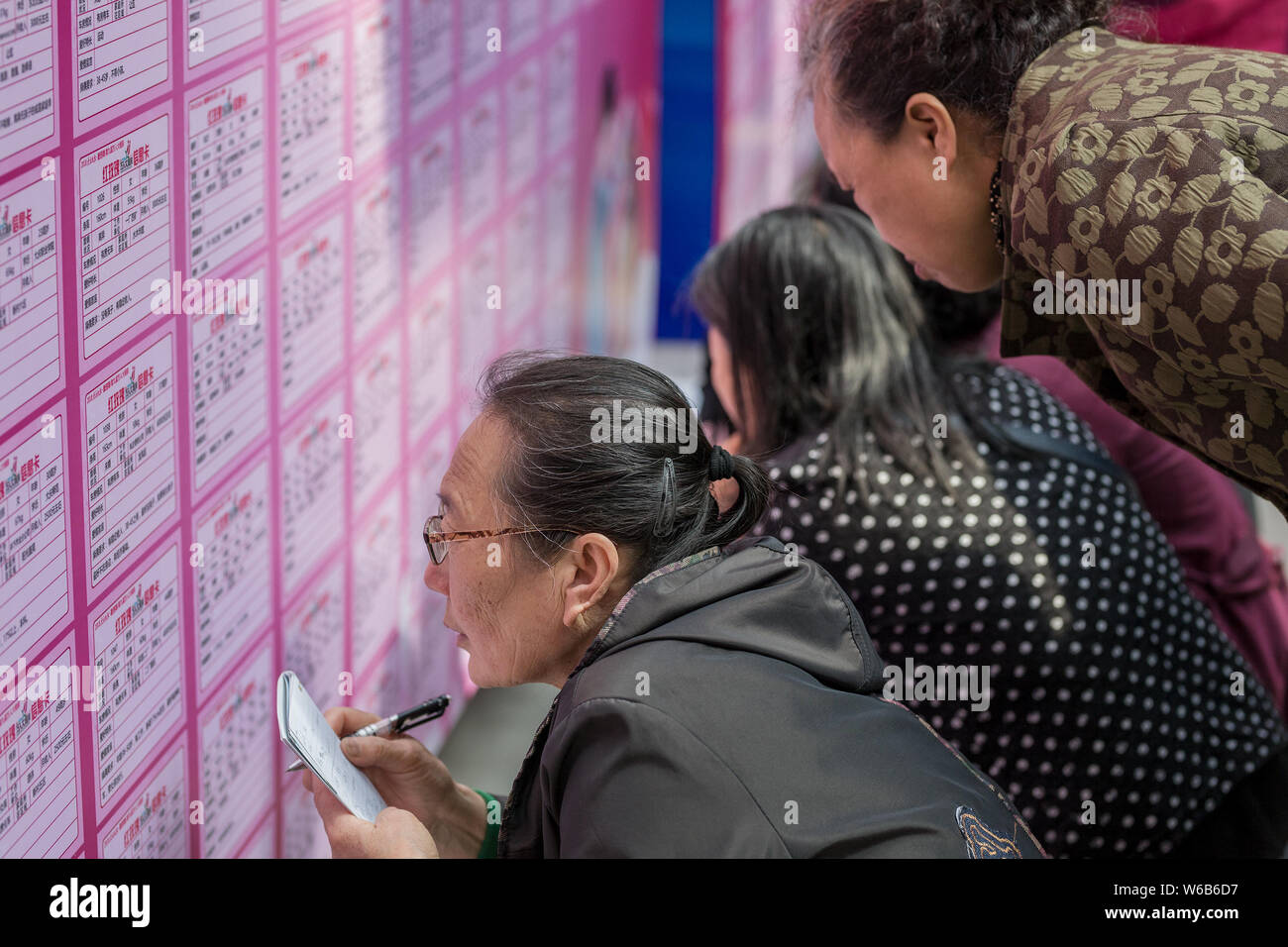 --FILE--genitori cinesi guardare e scattare foto di poster che mostra le informazioni personali di persone non sposate per il loro singolo bambini durante un matchmaki Foto Stock