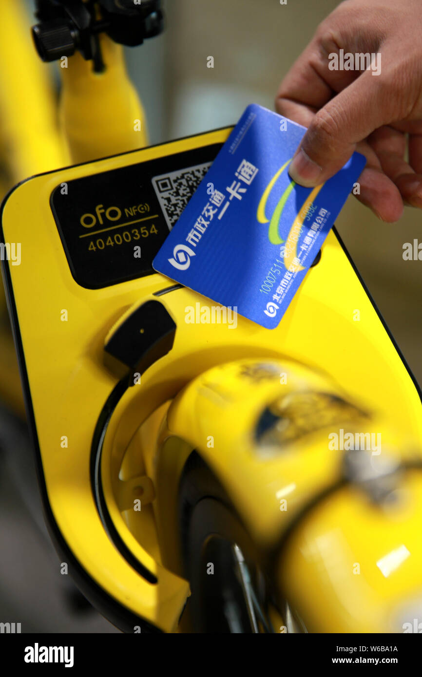 Uno studente di sfiorare il suo trasporto pubblico scheda su una bicicletta cinese di bike sharing service ofo con abilitati NFC bloccaggio intelligente per sbloccarlo presso il campus di Foto Stock