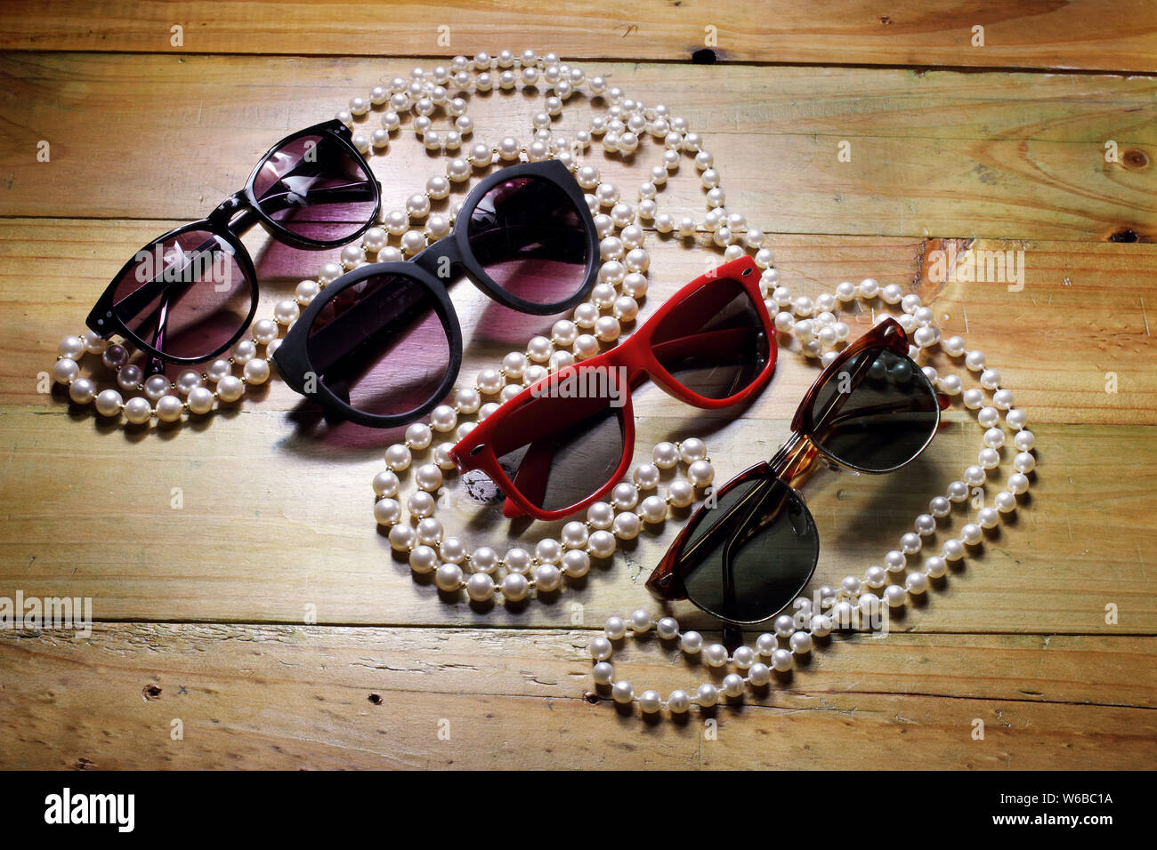 Occhiali da sole e la collana di perle su sfondo di legno Foto Stock