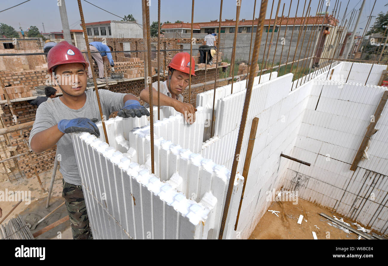Lavoratori cinesi l'uso di polistirene espanso (EPS) schiuma per costruire case nel villaggio Beiyuan, Hejin, città del nord della Cina nella provincia dello Shanxi, 27 maggio 2018. Due Foto Stock