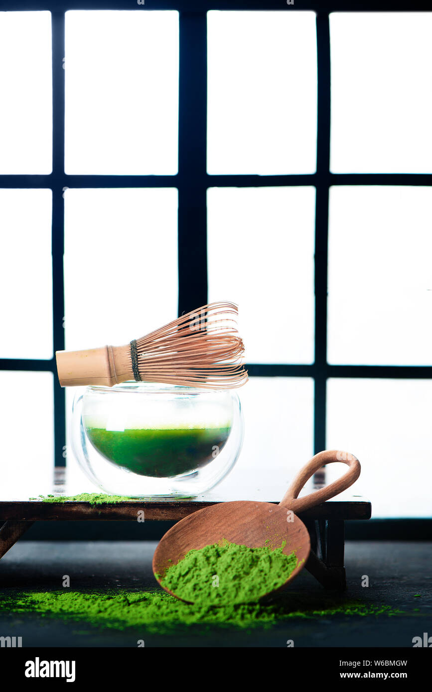 Tè verde Matcha in una doppia parete di vetro tazza di tè con una frusta di bambù. Shoji porte scorrevoli sfondo, tradizionale cerimonia giapponese Foto Stock