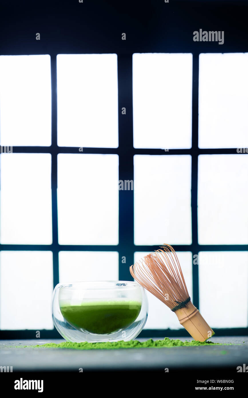 Tè verde Matcha in una doppia parete di vetro tazza di tè con una frusta di bambù. Shoji porte scorrevoli sfondo, tradizionale cerimonia giapponese Foto Stock