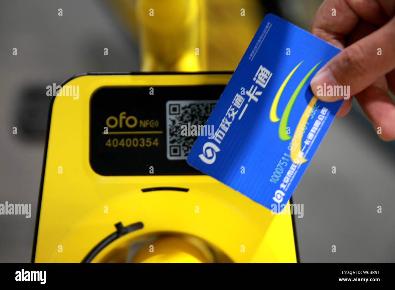 Uno studente di sfiorare il suo trasporto pubblico scheda su una bicicletta cinese di bike sharing service ofo con abilitati NFC bloccaggio intelligente per sbloccarlo presso il campus di Foto Stock