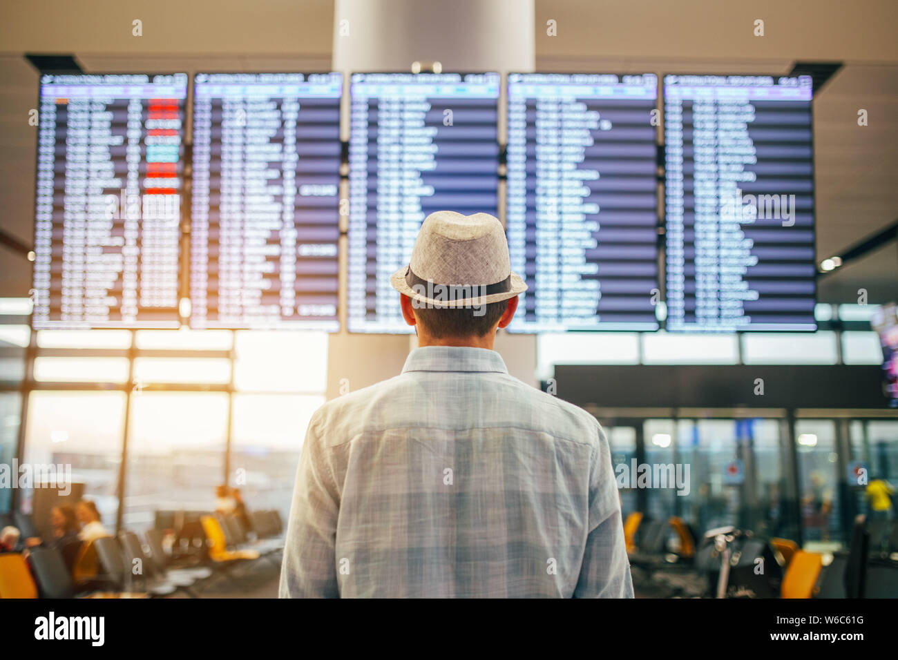 Solo traveler - uomo in piedi all'interno del terminal aeroportuale guardando un programma. Viaggi e trasporti immagine a tema. Foto Stock