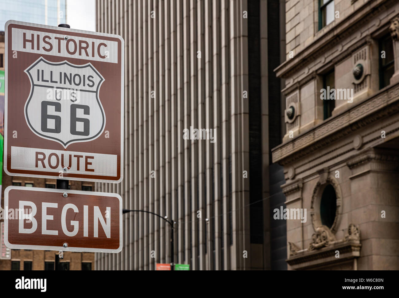 Route 66 Illinois iniziare cartello stradale a Chicago downtown della città. La facciata degli edifici dello sfondo. Route 66, madre road, il classico roadtrip storico NEGLI STATI UNITI Foto Stock