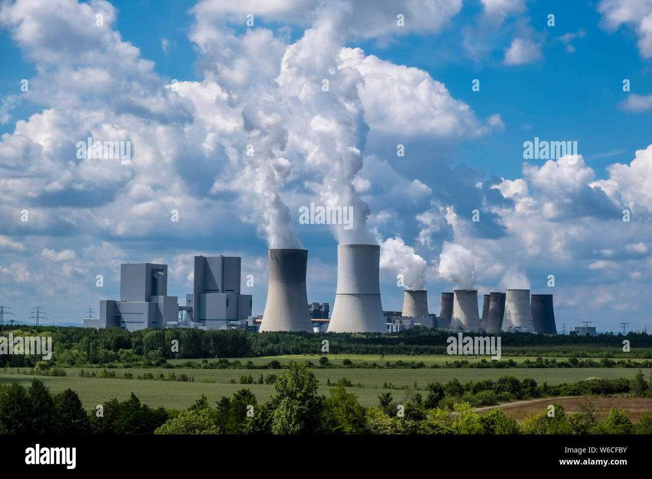 Gli edifici e la cottura a vapore delle torri di raffreddamento di un impianto alimentato a carbone nel paesaggio agricolo Foto Stock