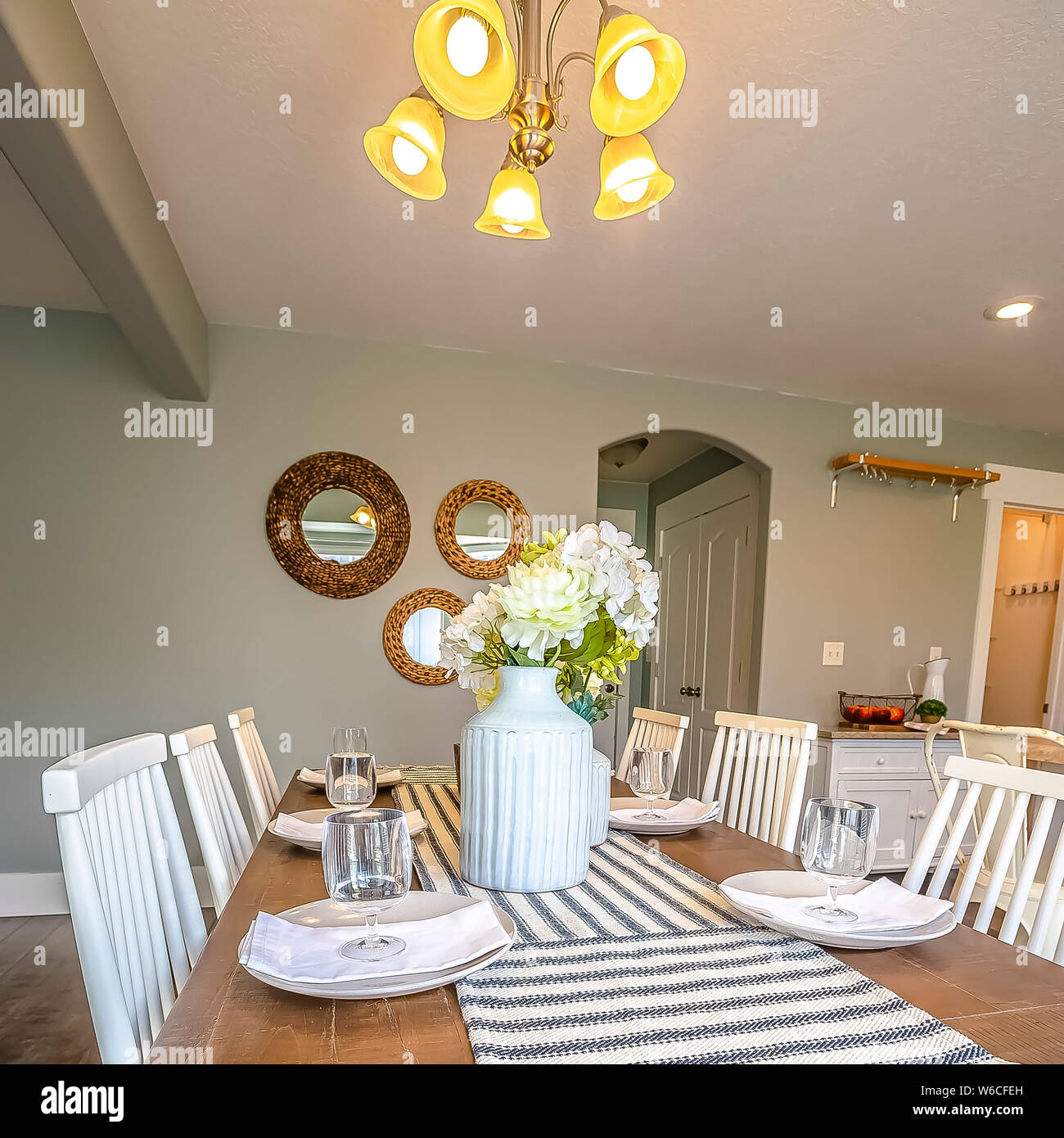 Cornice quadrata sala da pranzo interna di una casa marrone con tavolo in  legno e sedie bianche Foto stock - Alamy